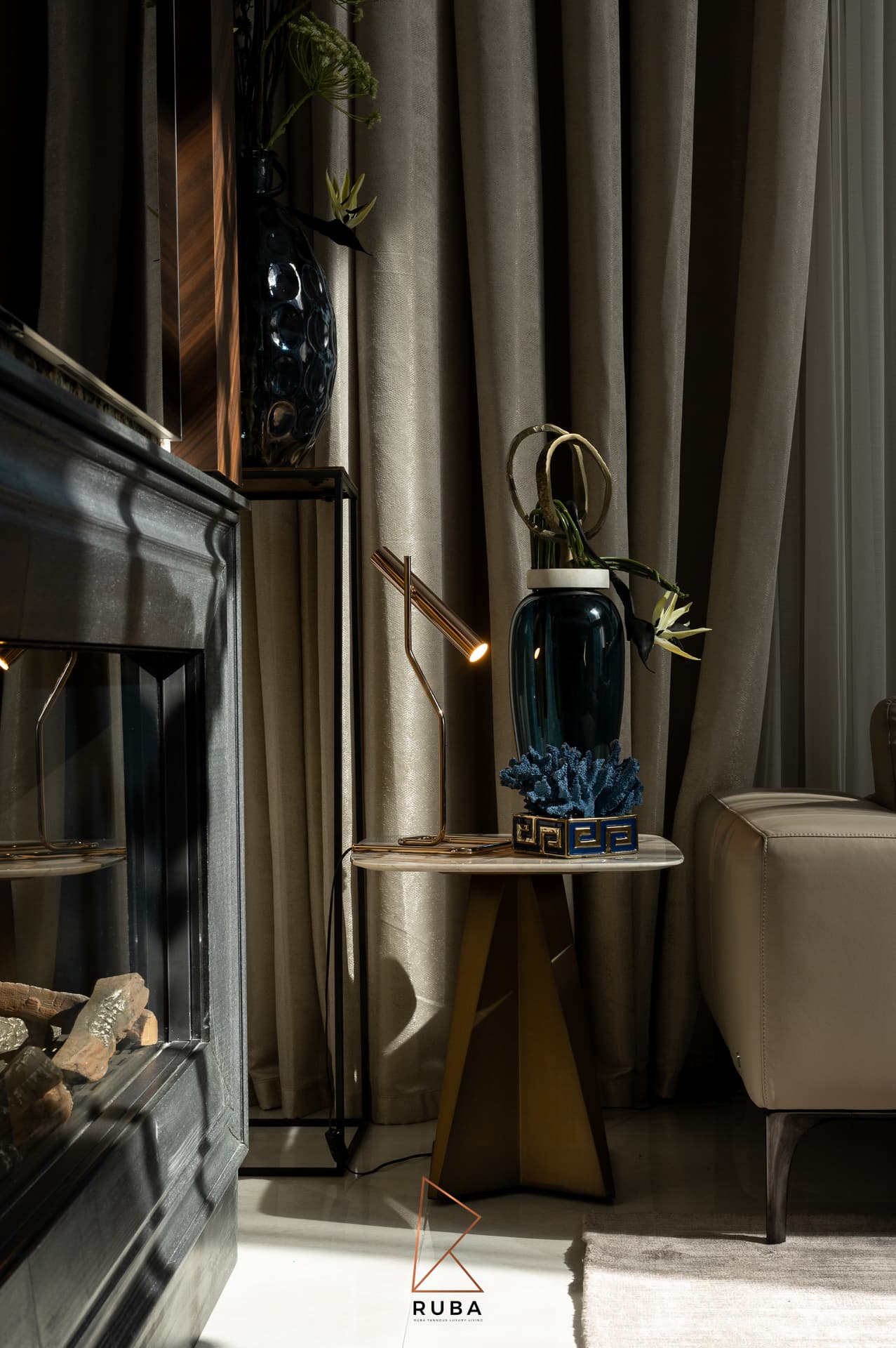 Shaded corner beside the fireplace with a brass lamp, blue vase and coral on a side table in the living room of Patagonia