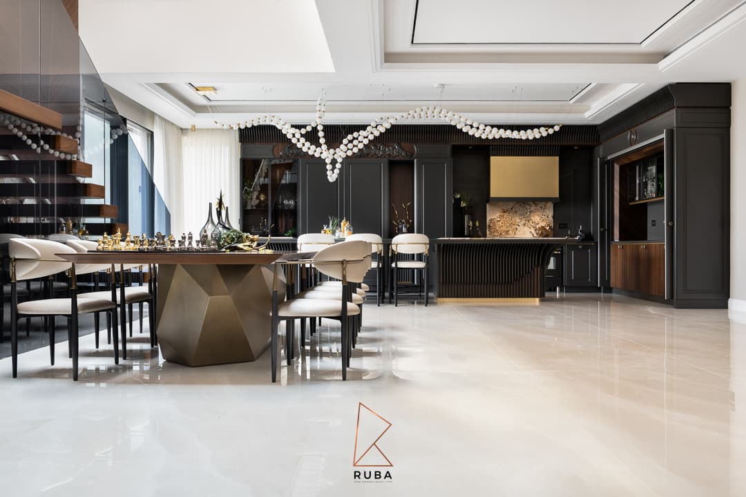 Open dining room with a long faceted-base table and cream chairs leading to the black kitchen in Patagonia