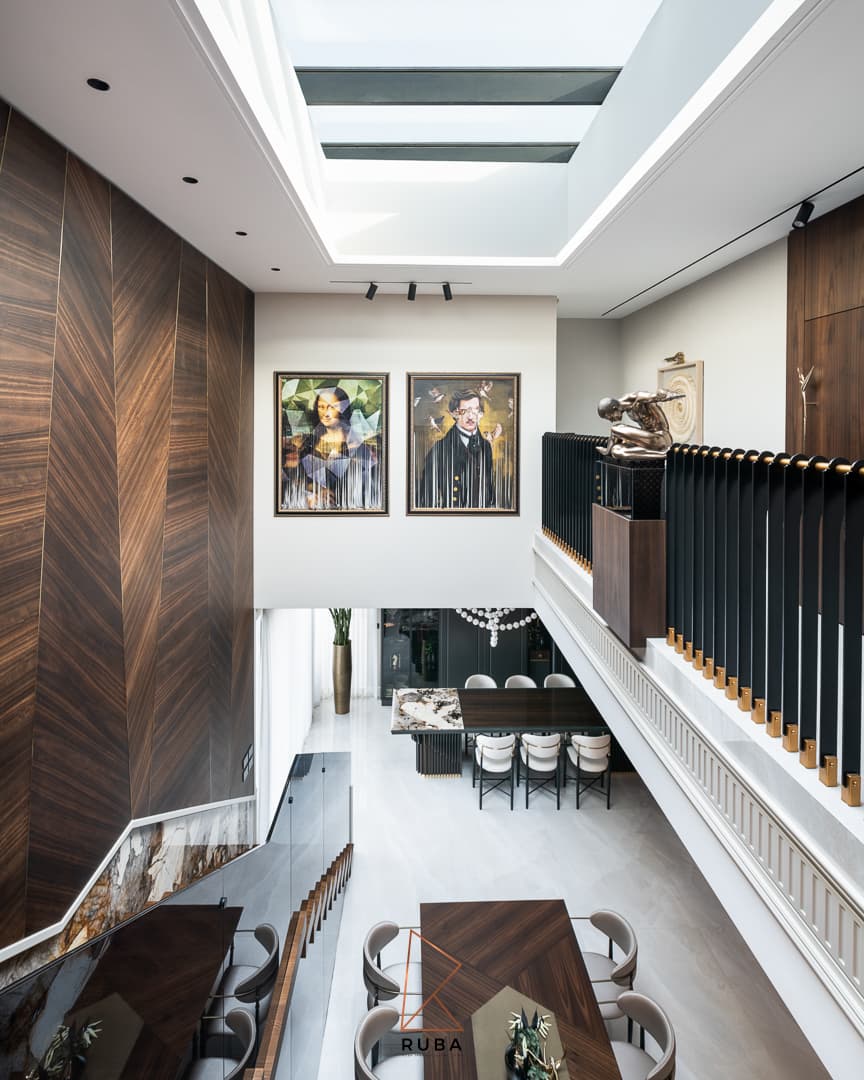View from the upper gallery down to the dining room past a chevron walnut wall and skylight in Patagonia