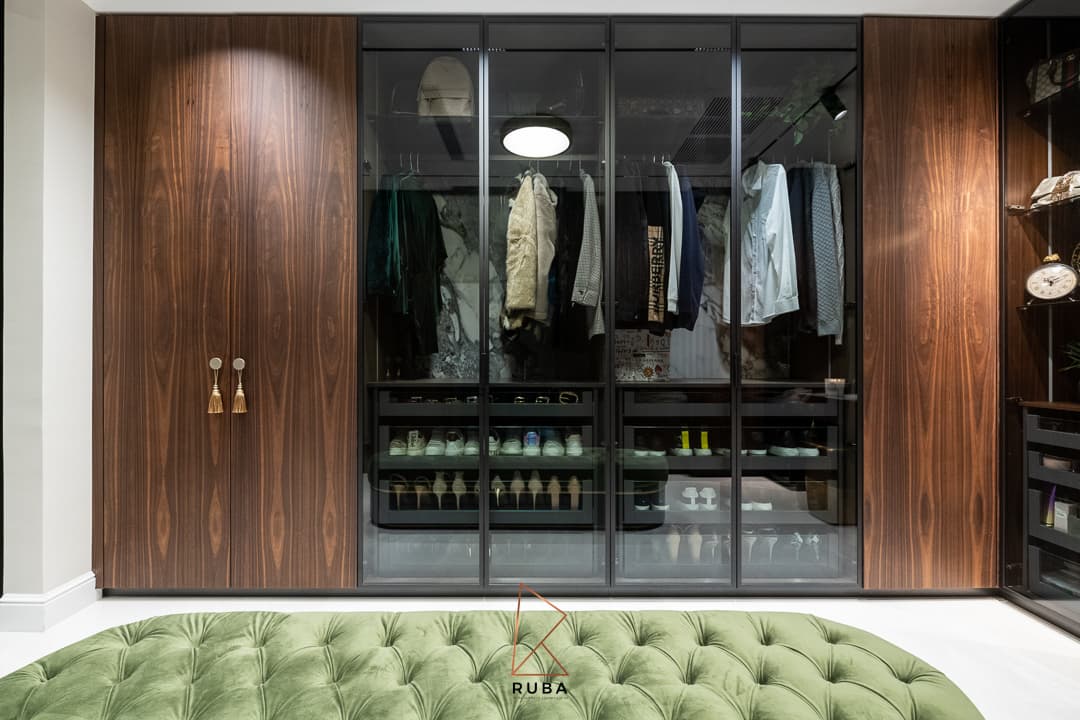 Walnut wardrobe doors with tassel pulls flanking a glass-front closet for clothes and shoes in the dressing room of Patagonia
