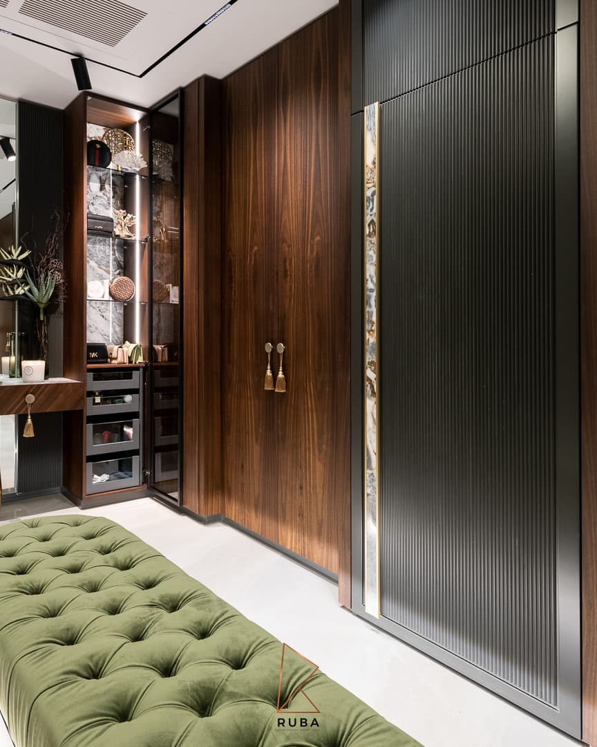 Fluted black door with a vertical veined stone inlay beside walnut wardrobes in the dressing room of Patagonia