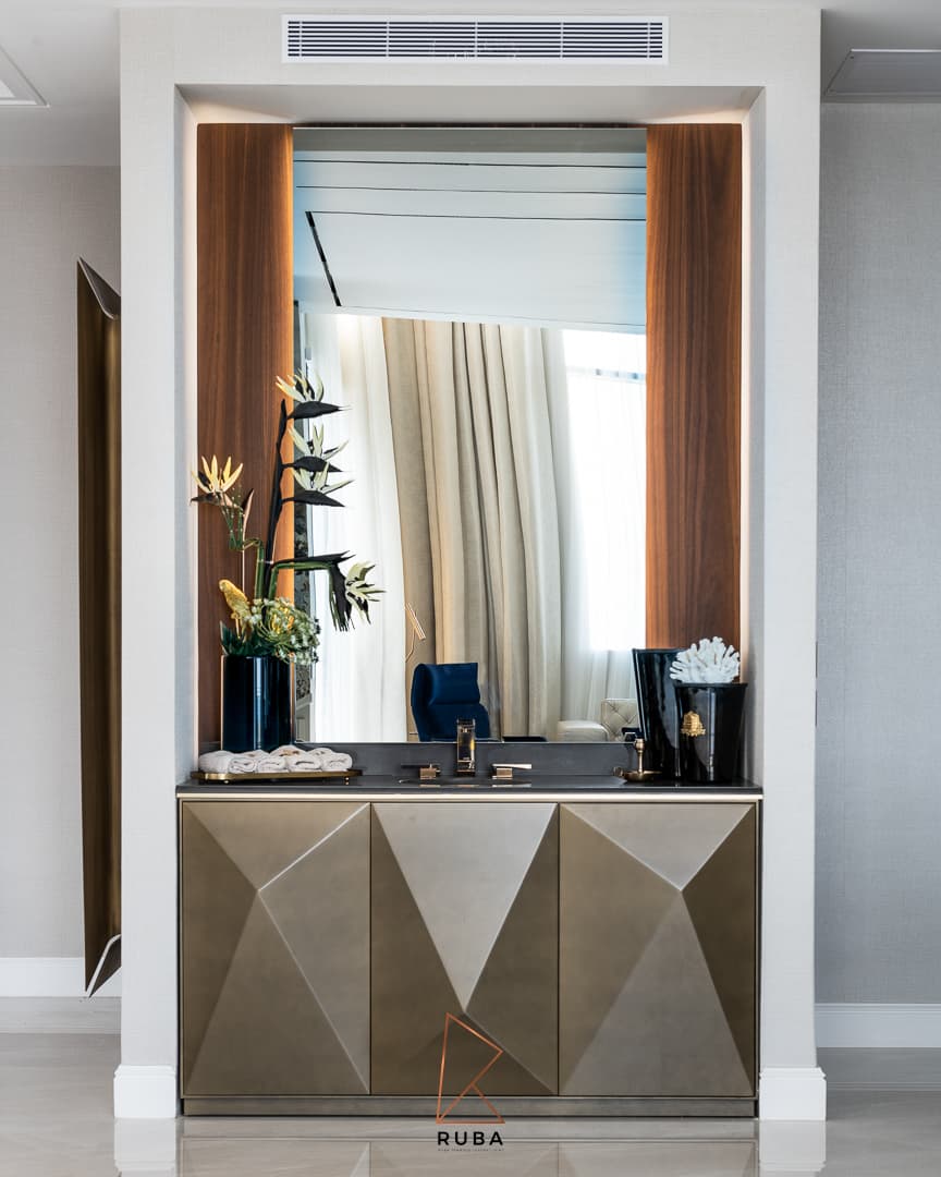 Entrance vanity with faceted brass cabinet doors and a walnut-lined mirror niche with hidden lighting in Patagonia