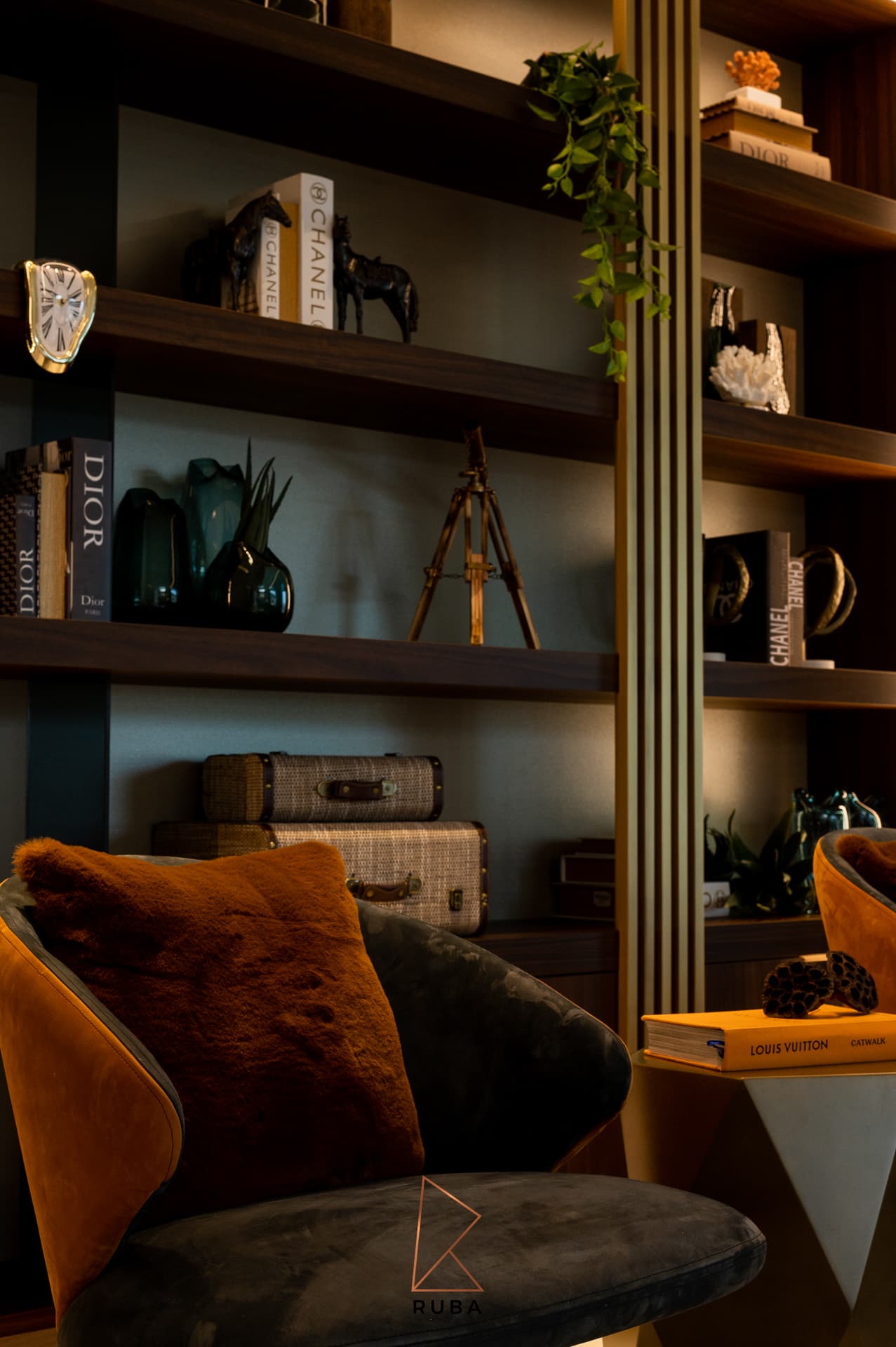 Walnut shelving with glass vases, woven cases and a tripod accent behind a lounge chair in the family room of Patagonia