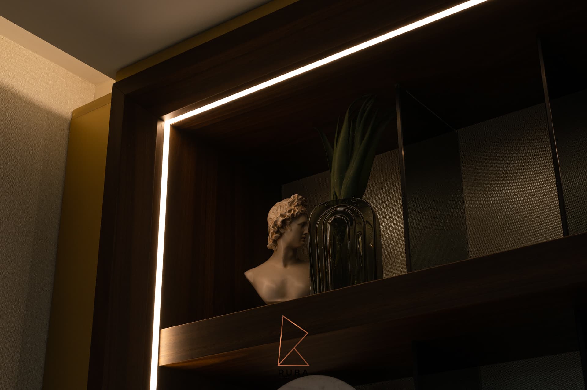 Classical bust and smoked glass vase on a walnut shelf edged by a warm LED strip in the family room of Patagonia