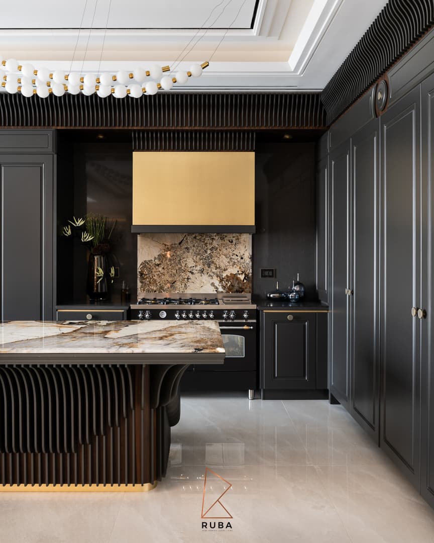 Black panelled kitchen with a brushed brass range hood, veined stone backsplash and a stone island on a fluted dark wood base in Patagonia