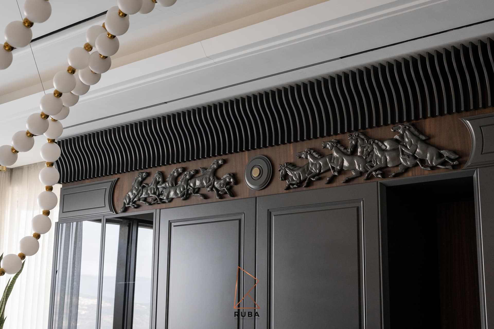 Horse relief frieze and wave-fluted cornice framed by white glass bead pendant strands in the kitchen of Patagonia