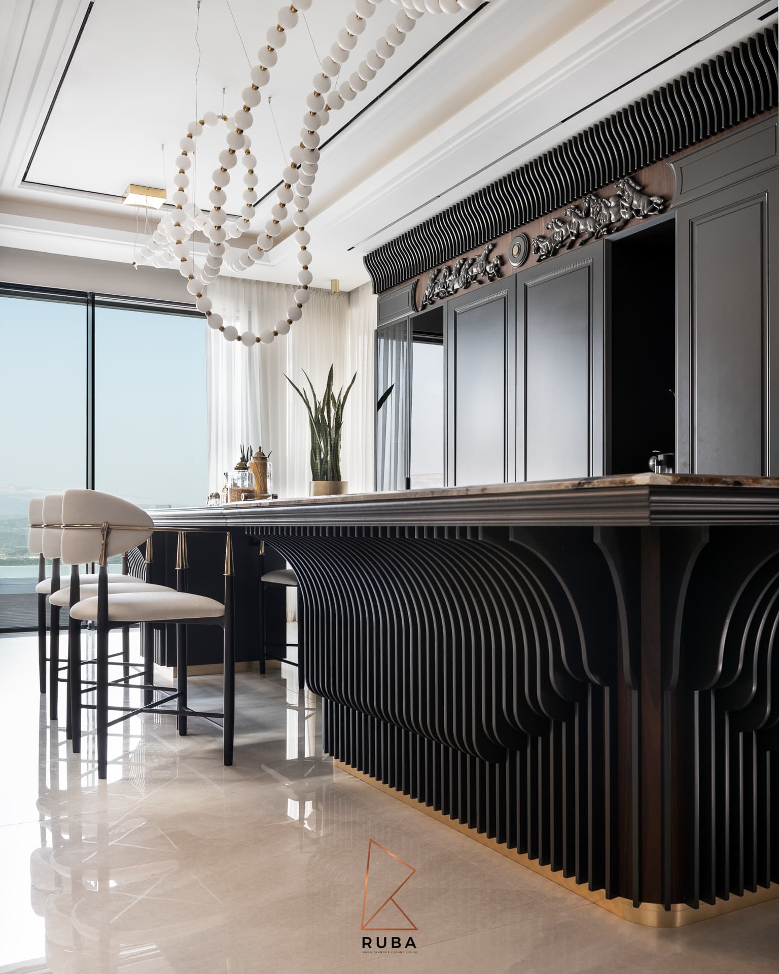 Kitchen island with a sculpted fluted black base, cream counter stools and a wave-fluted cornice in Patagonia