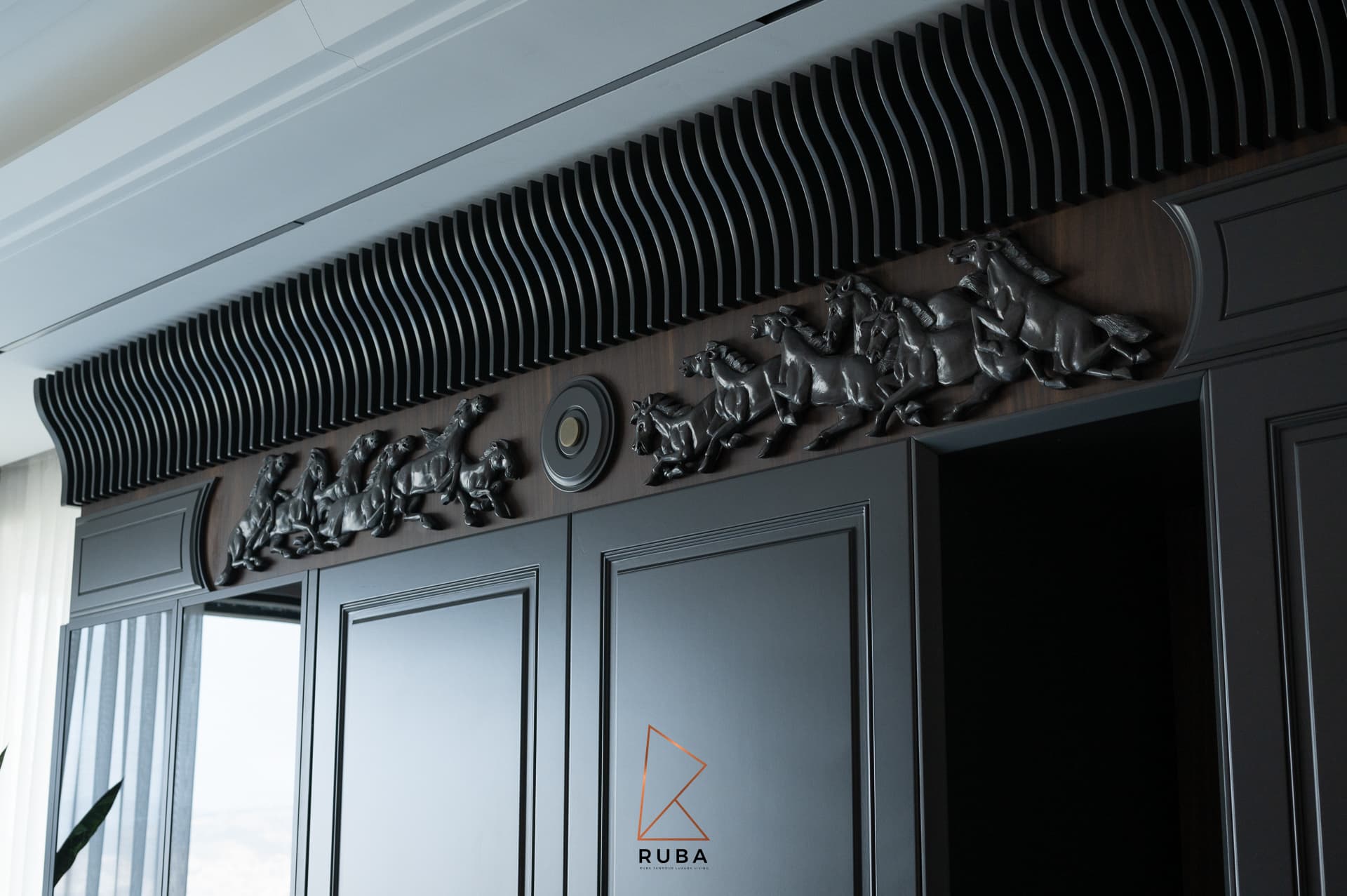 Sculpted running-horse relief frieze under a wave-fluted cornice above black cabinetry in the kitchen of Patagonia