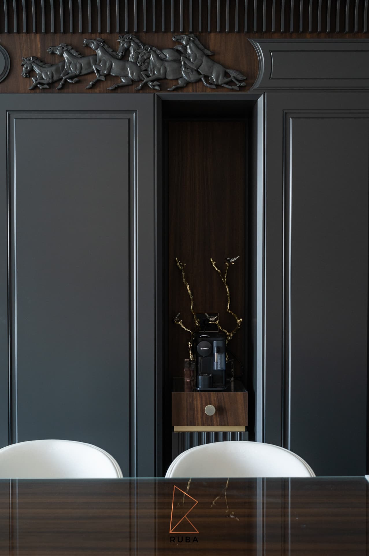 Walnut-lined coffee niche between black panelled doors below a horse relief frieze in the kitchen of Patagonia