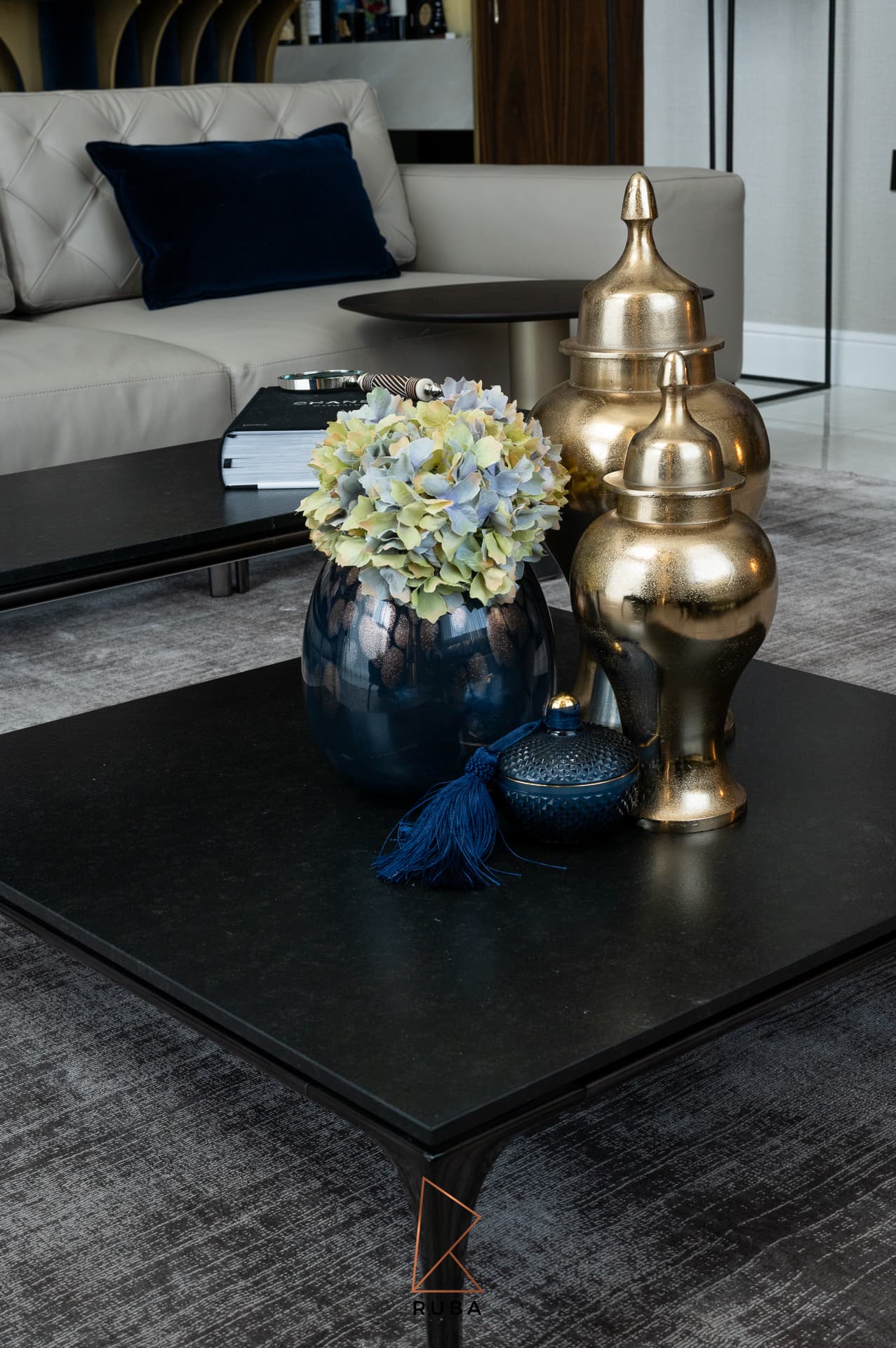 Black coffee table styled with brass ginger jars, a blue glass vase and hydrangeas in the living room of Patagonia