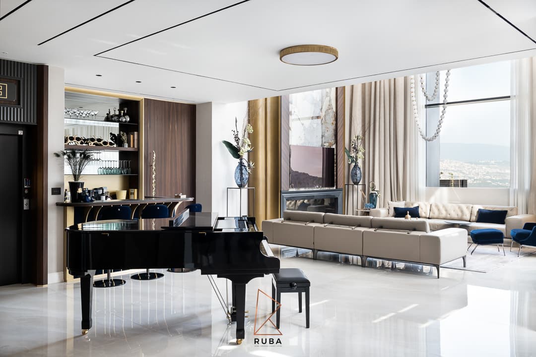 Open living area with a black grand piano, a brass-finned bar and long leather sofas under a slim-lined ceiling in Patagonia