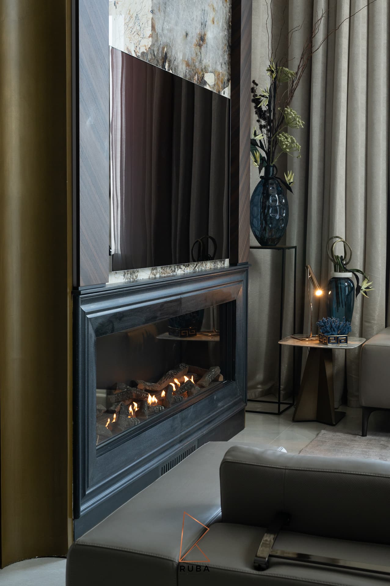 Vertical view of the fireplace and television wall between walnut panels and a fluted brass column in the living room of Patagonia