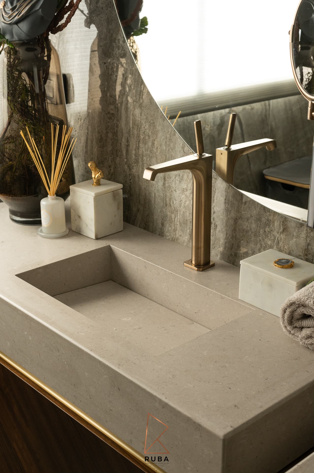 Integrated stone basin with a tall brushed brass faucet and marble accessories in the master bathroom of Patagonia