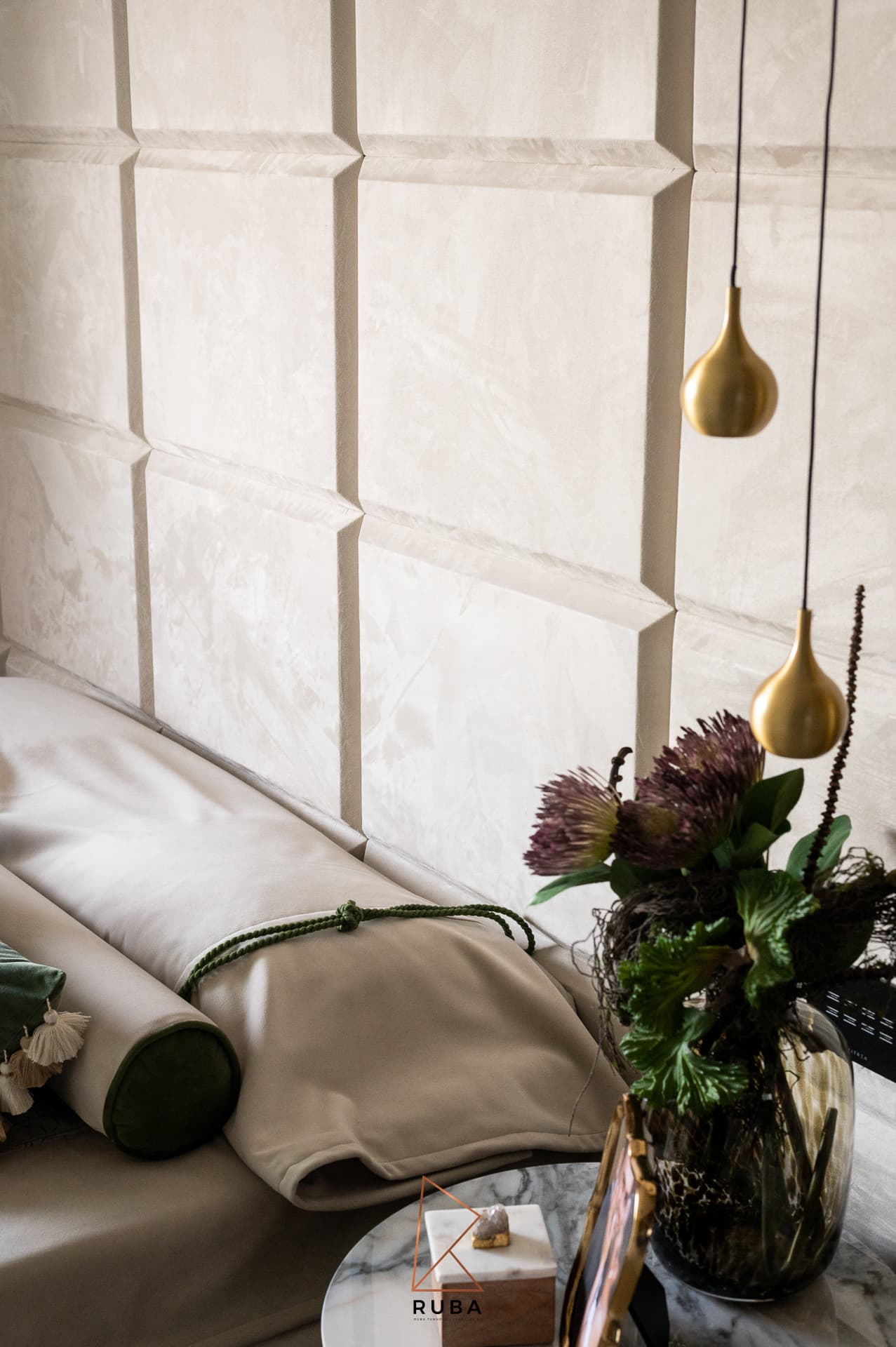Brass teardrop pendants hanging beside a padded cream headboard and protea arrangement in the master bedroom of Patagonia
