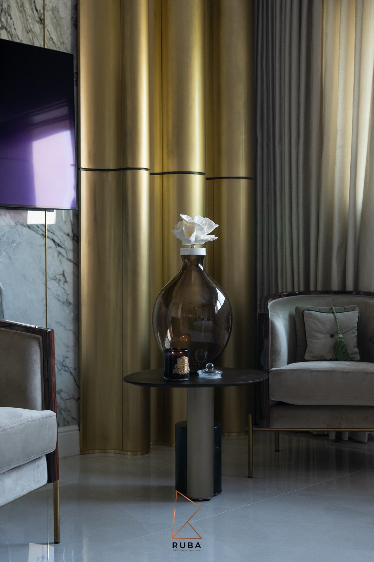 Fluted brass column wall behind a smoked glass vase on a round side table in the master bedroom of Patagonia