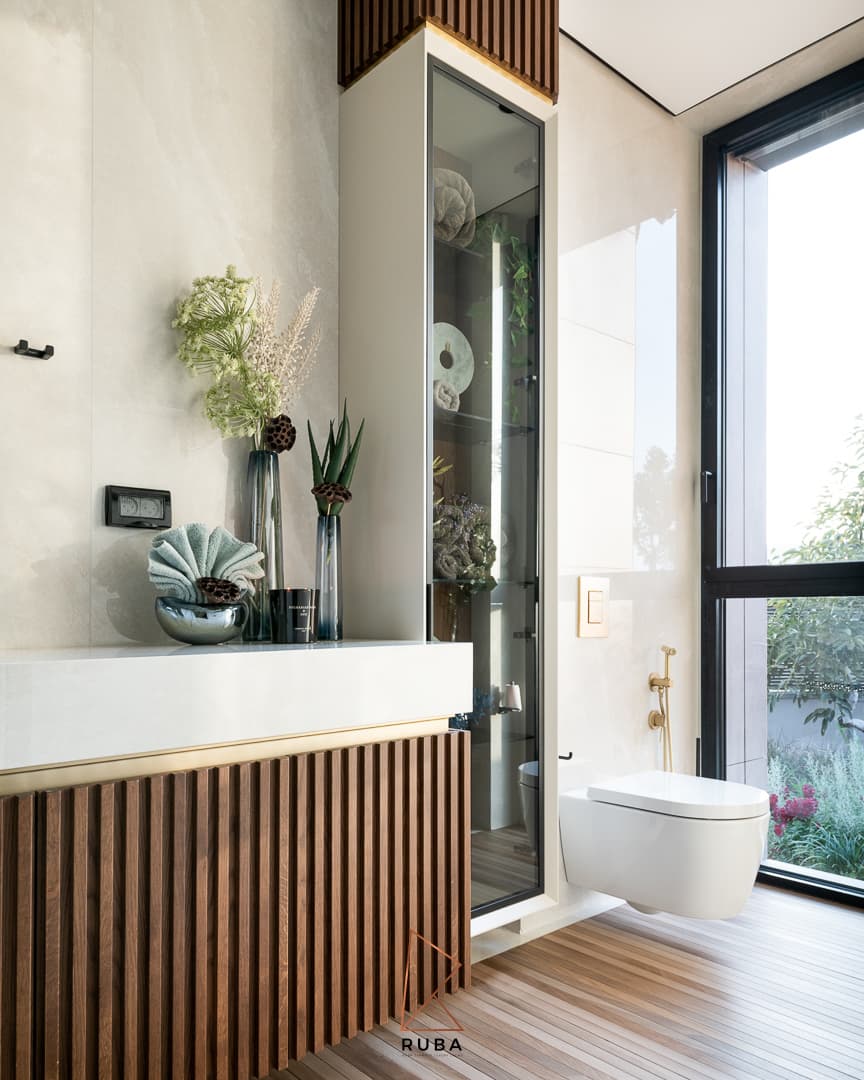 Ribbed wood vanity, glass display cabinet and wall-hung toilet beside a garden window in the powder bathroom of Patagonia
