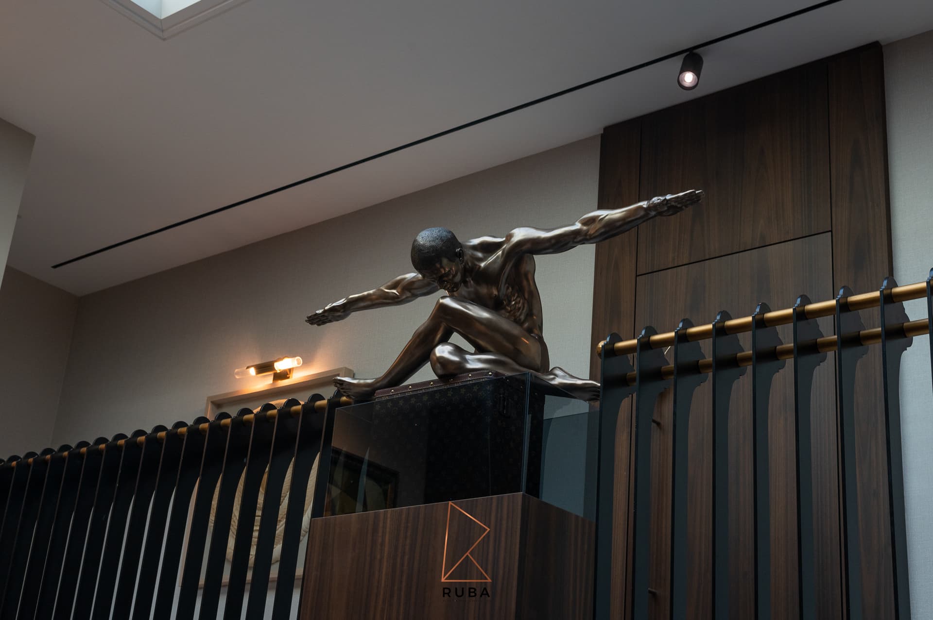 Low view of a bronze figure sculpture on the black and brass balustrade at the top of the staircase in Patagonia