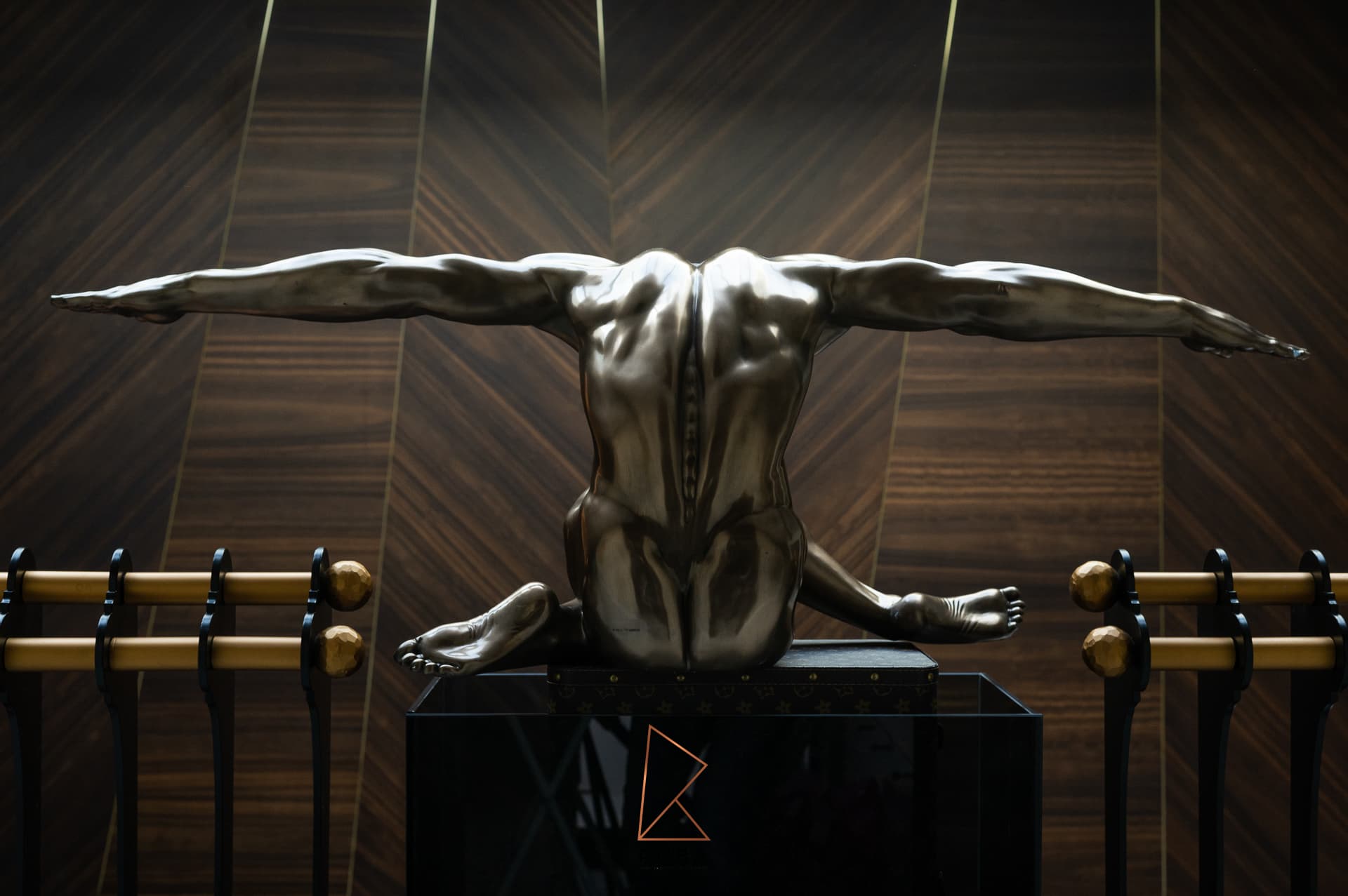 Bronze figure sculpture with outstretched arms set against a chevron walnut wall on the staircase landing of Patagonia