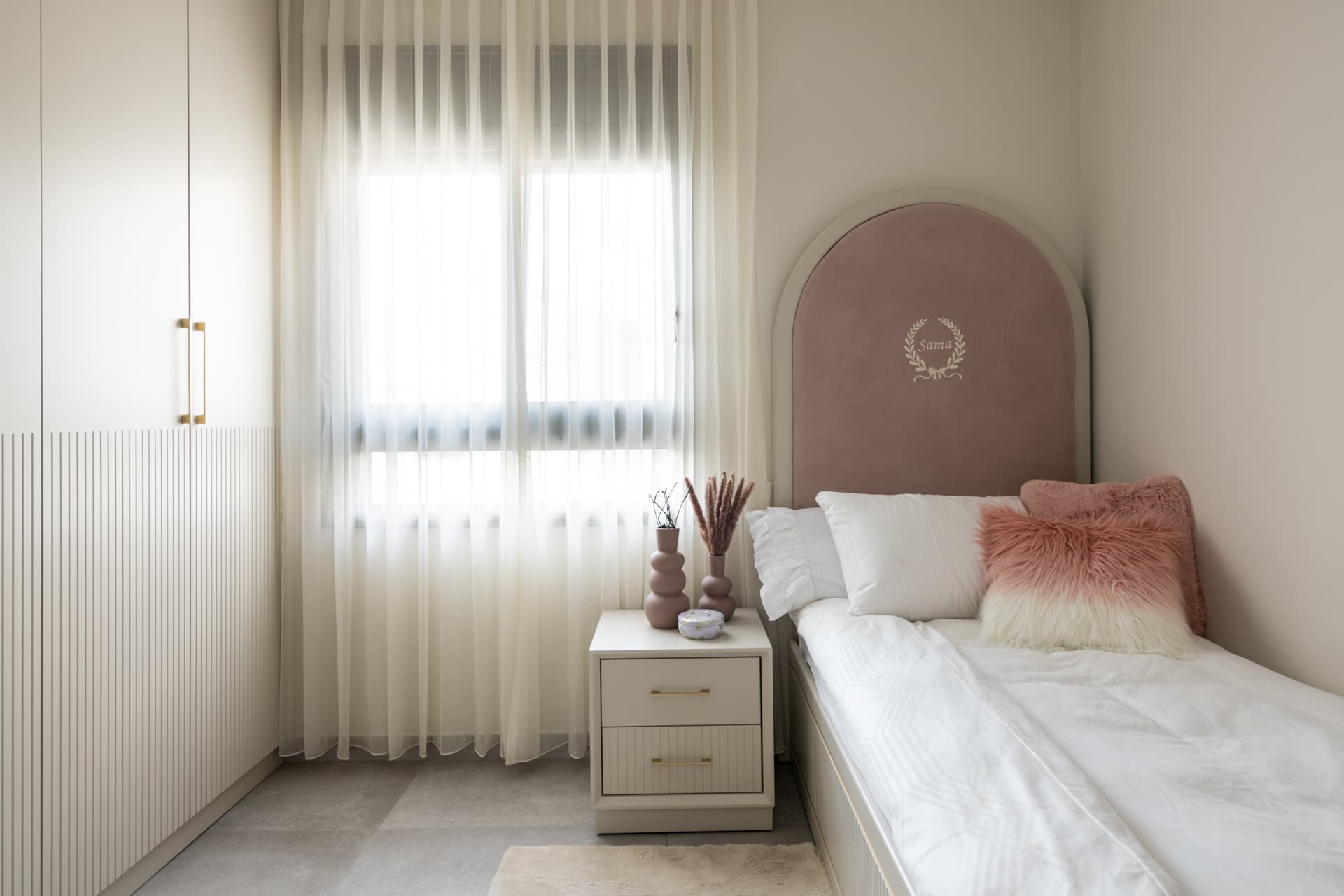 Arched blush velvet headboard, fluted cream wardrobe and sheer curtains around a single bed in the girls bedroom of Pistachio