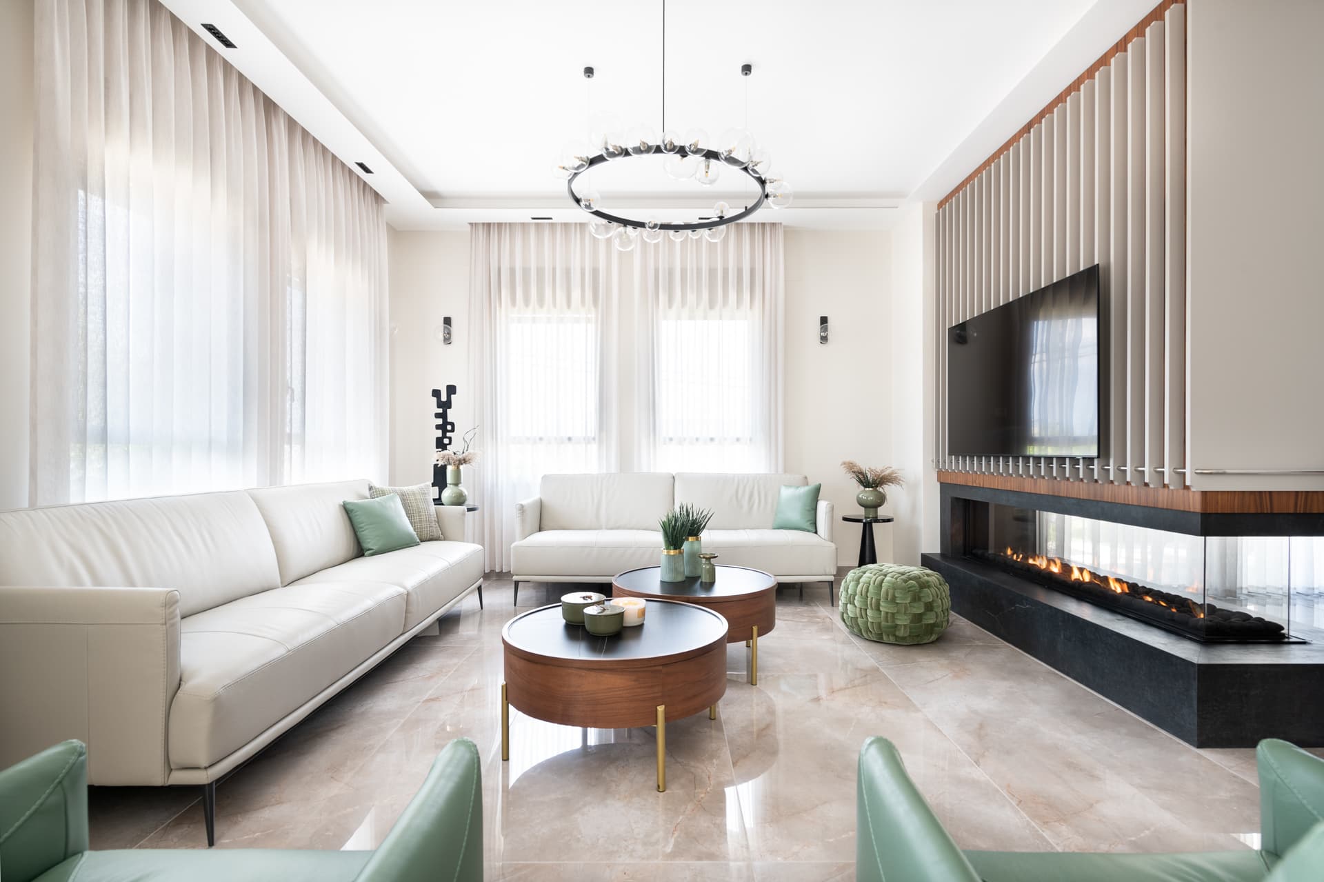 Cream sofas around nested walnut coffee tables, facing a slatted media wall over a linear fireplace in the living room of Pistachio