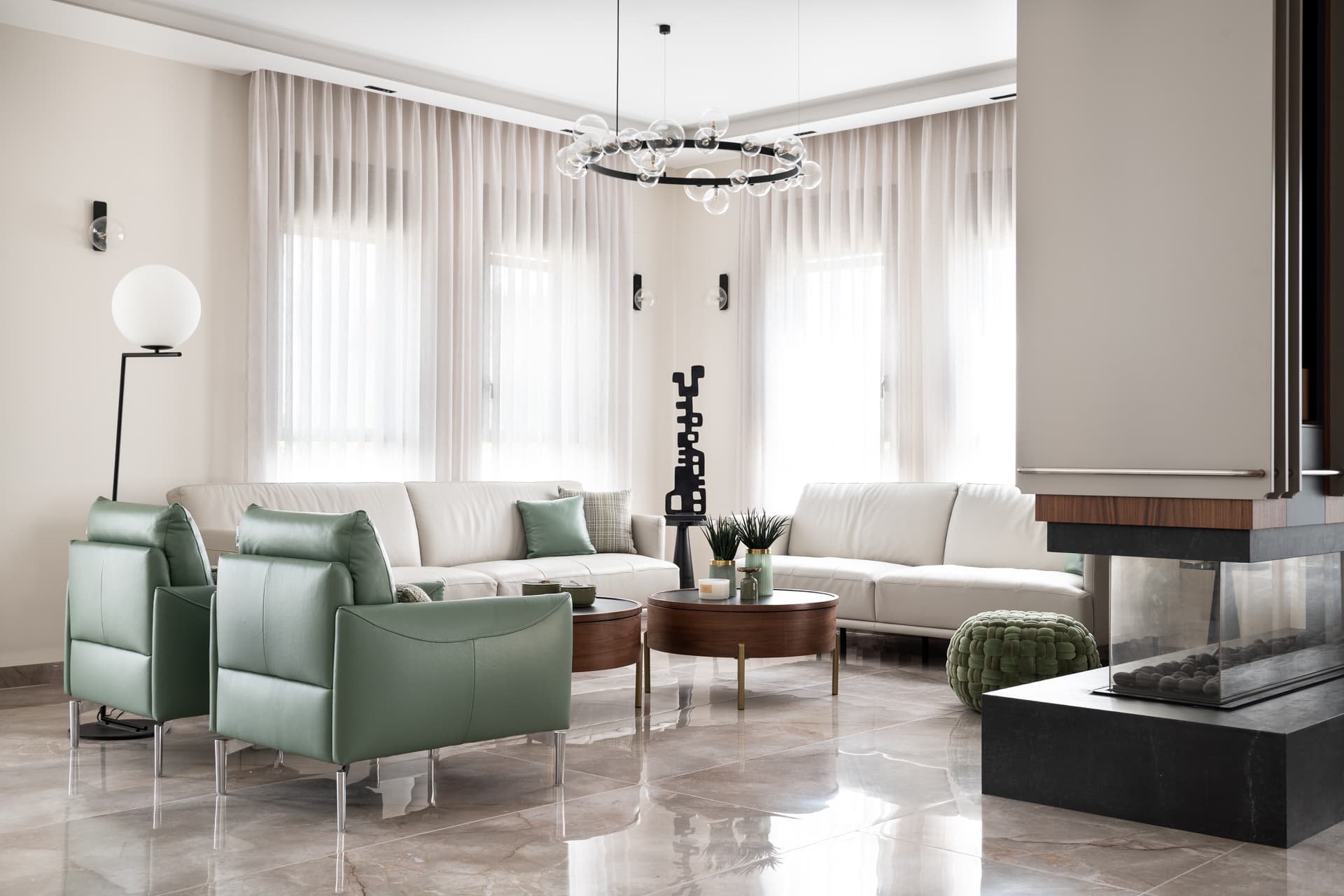 Sage leather armchairs, cream sofas and a glass-globe ring chandelier beside the open fireplace in the living room of Pistachio