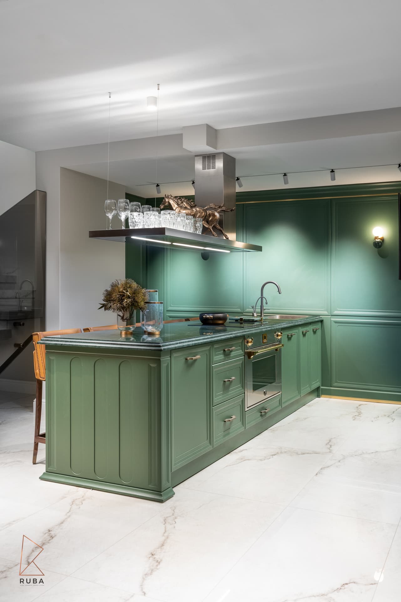 Basement kitchenette with forest-green panelled cabinetry, a suspended shelf of glassware and a green marble counter in The Last Supper