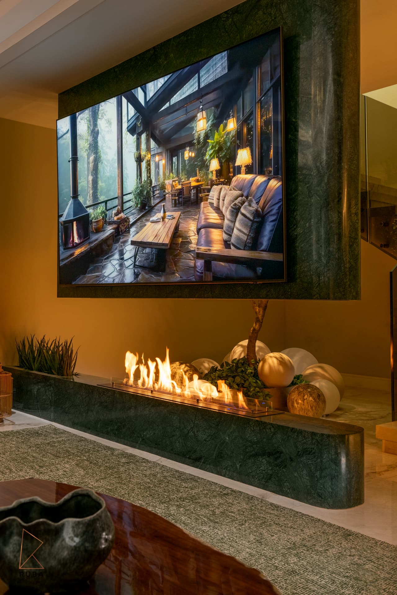 Basement lounge with a linear fire feature set in a green marble wall beneath a large screen in The Last Supper