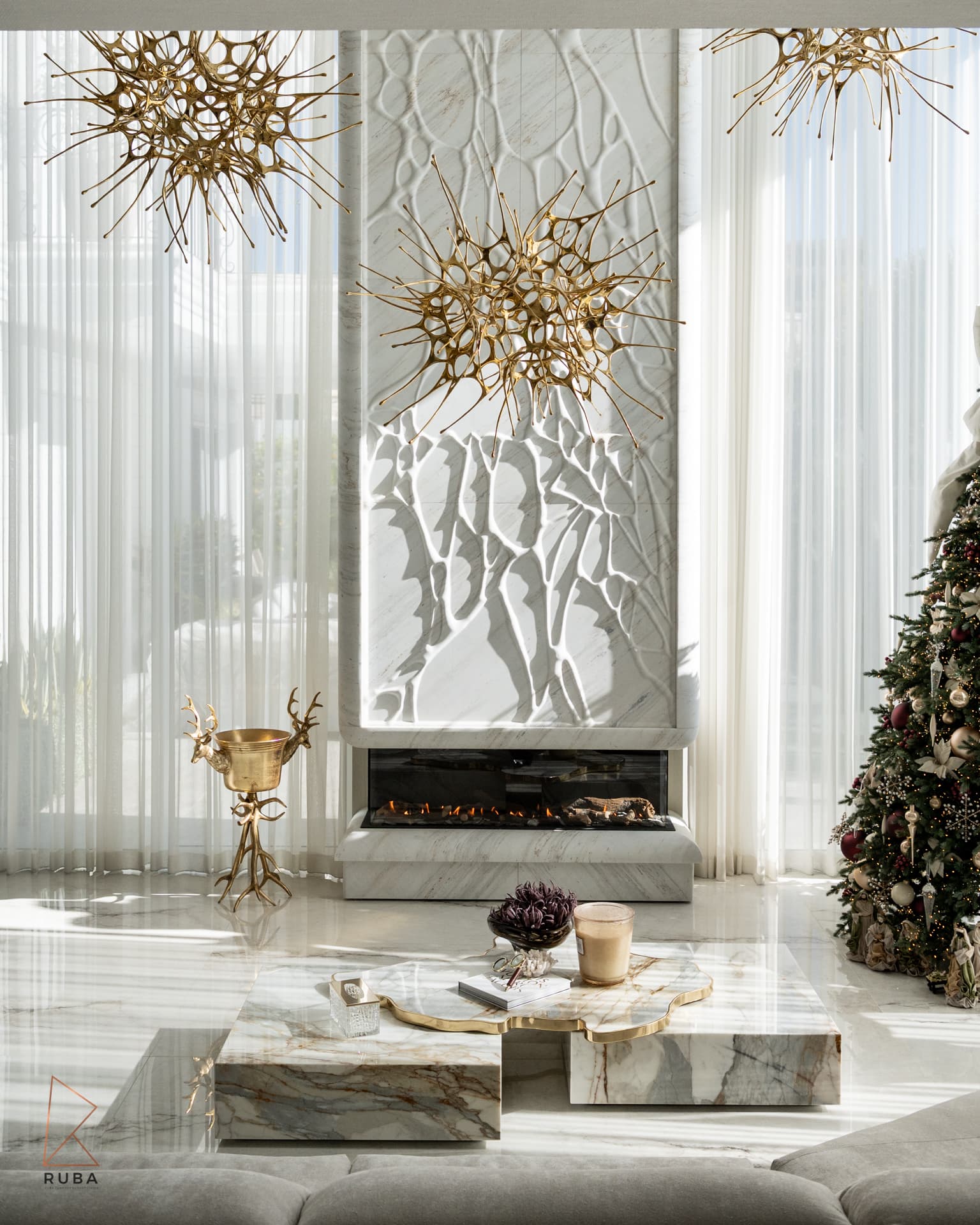 Carved white stone fireplace column behind stone block coffee tables and gold starburst chandeliers in The Last Supper
