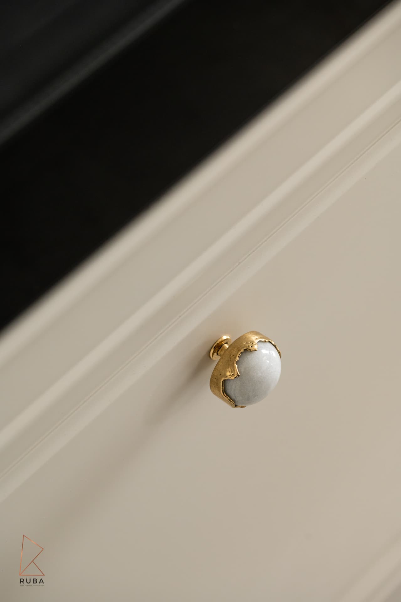 Round white stone knob with a raw gold rim on a cream panelled drawer front in The Last Supper