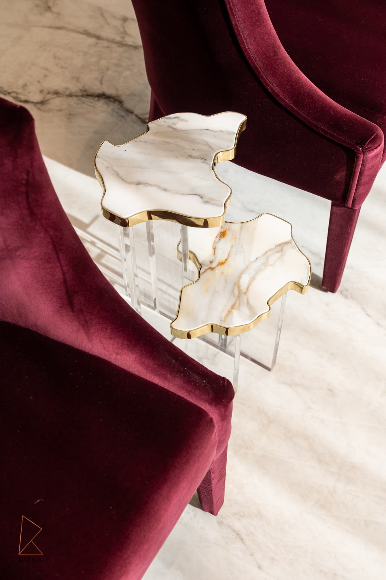 Burgundy velvet armchairs around nesting side tables with veined stone tops and gold edges in The Last Supper