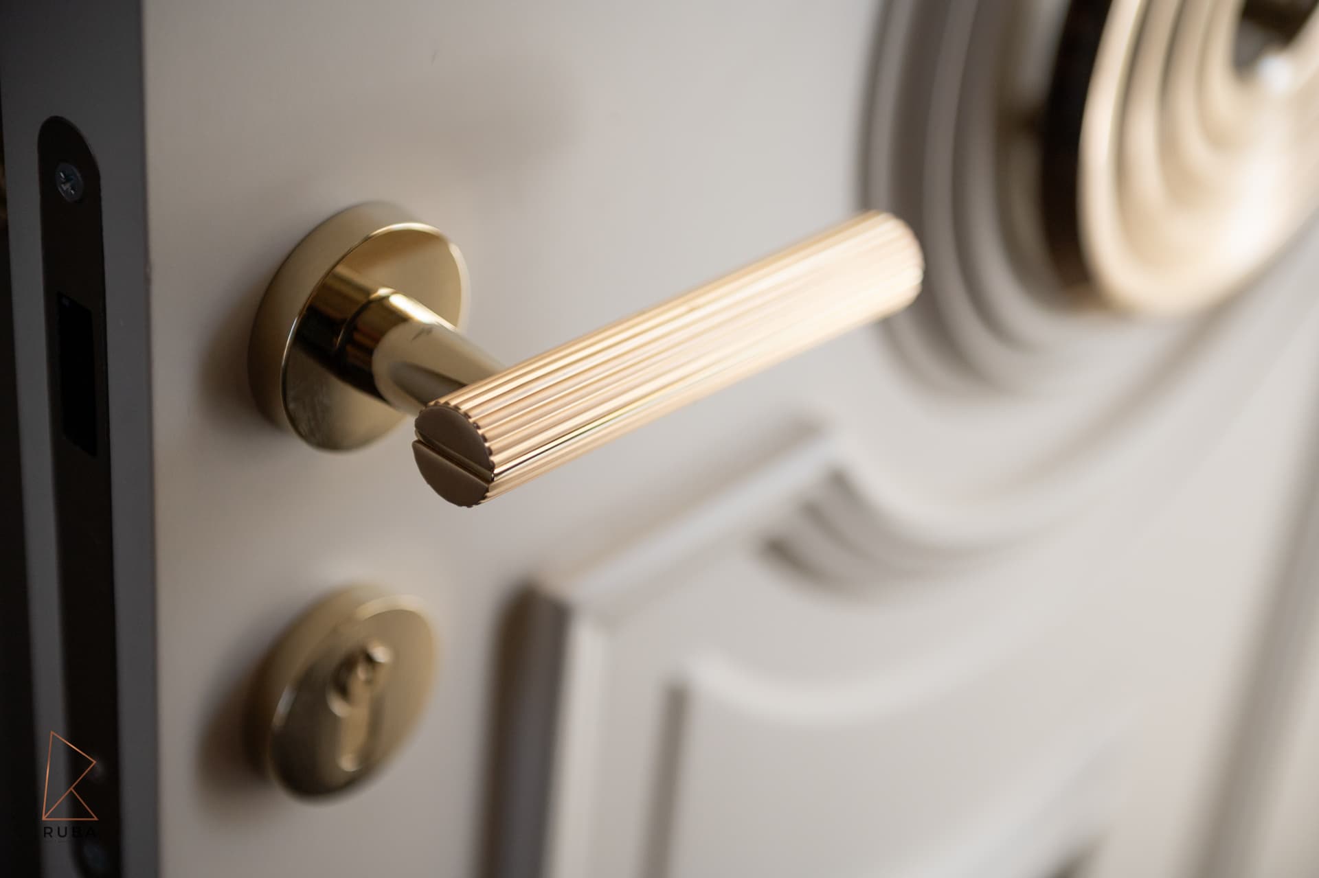 Fluted brass door lever and escutcheon on a sculpted cream door with carved circular panels in The Last Supper