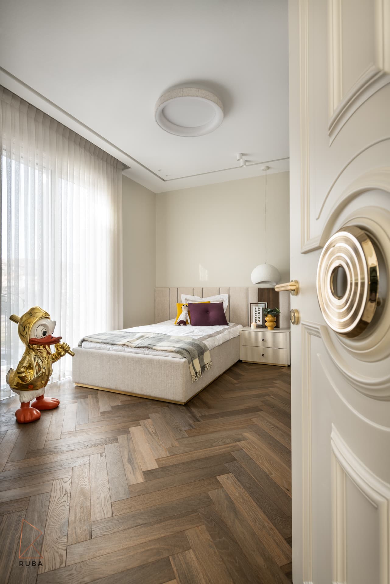 Kids bedroom seen through a sculpted cream door with herringbone oak floor and a gold duck sculpture in The Last Supper