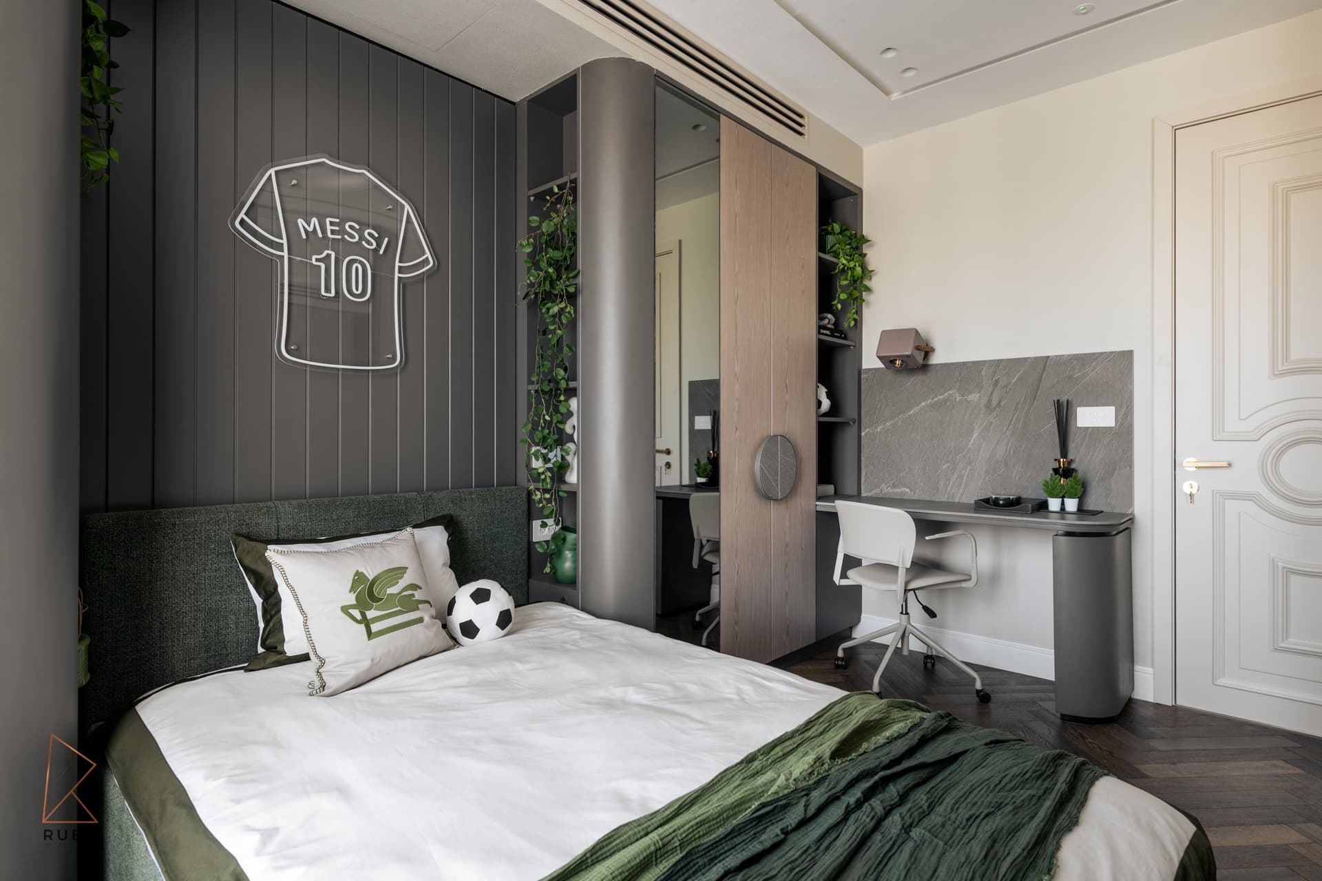 Kids bedroom desk corner with a grey stone backsplash beside a curved column and green bed in The Last Supper
