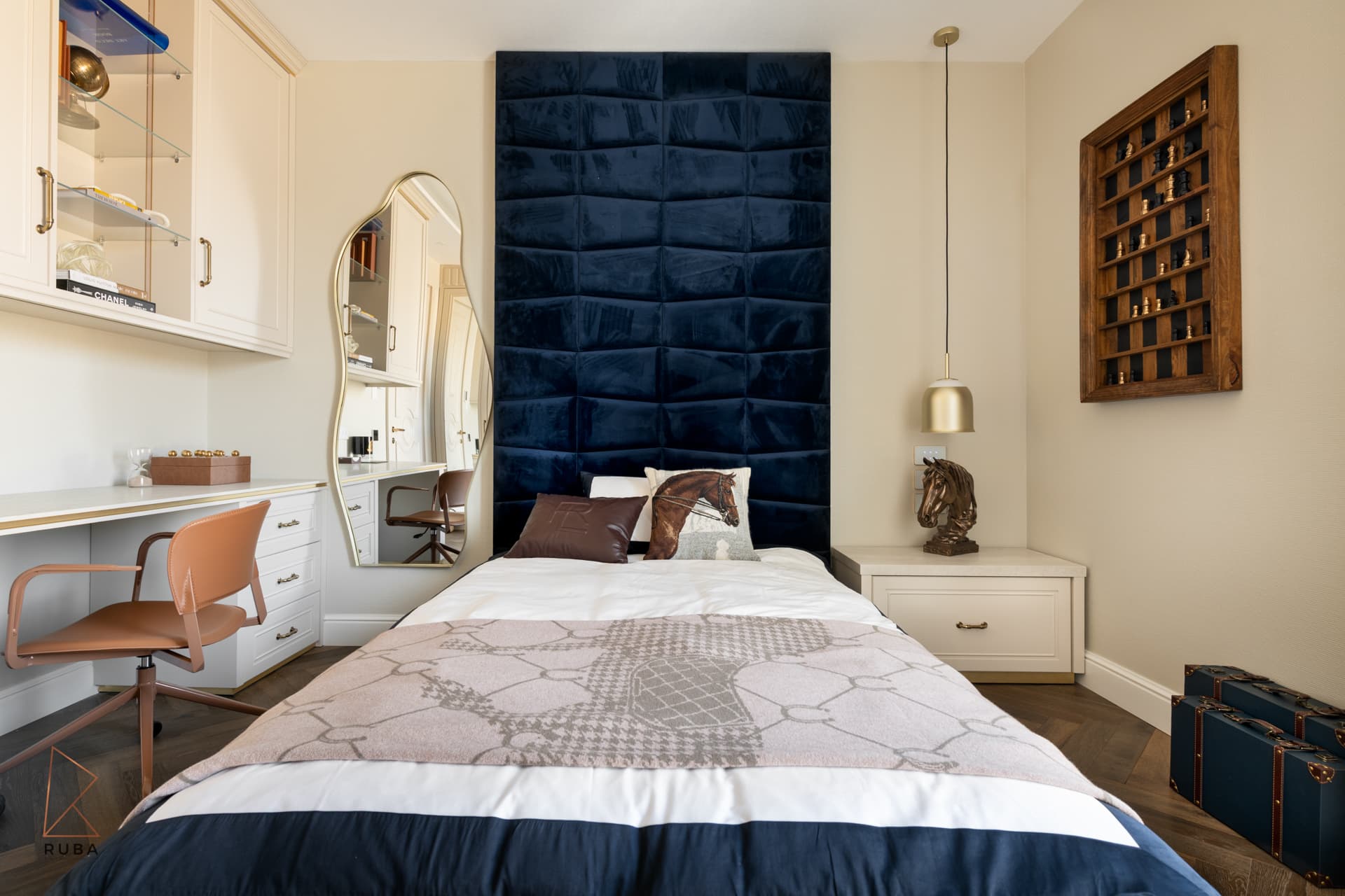 Kids bedroom with a padded navy velvet headboard wall, built-in desk and wall-mounted display case in The Last Supper