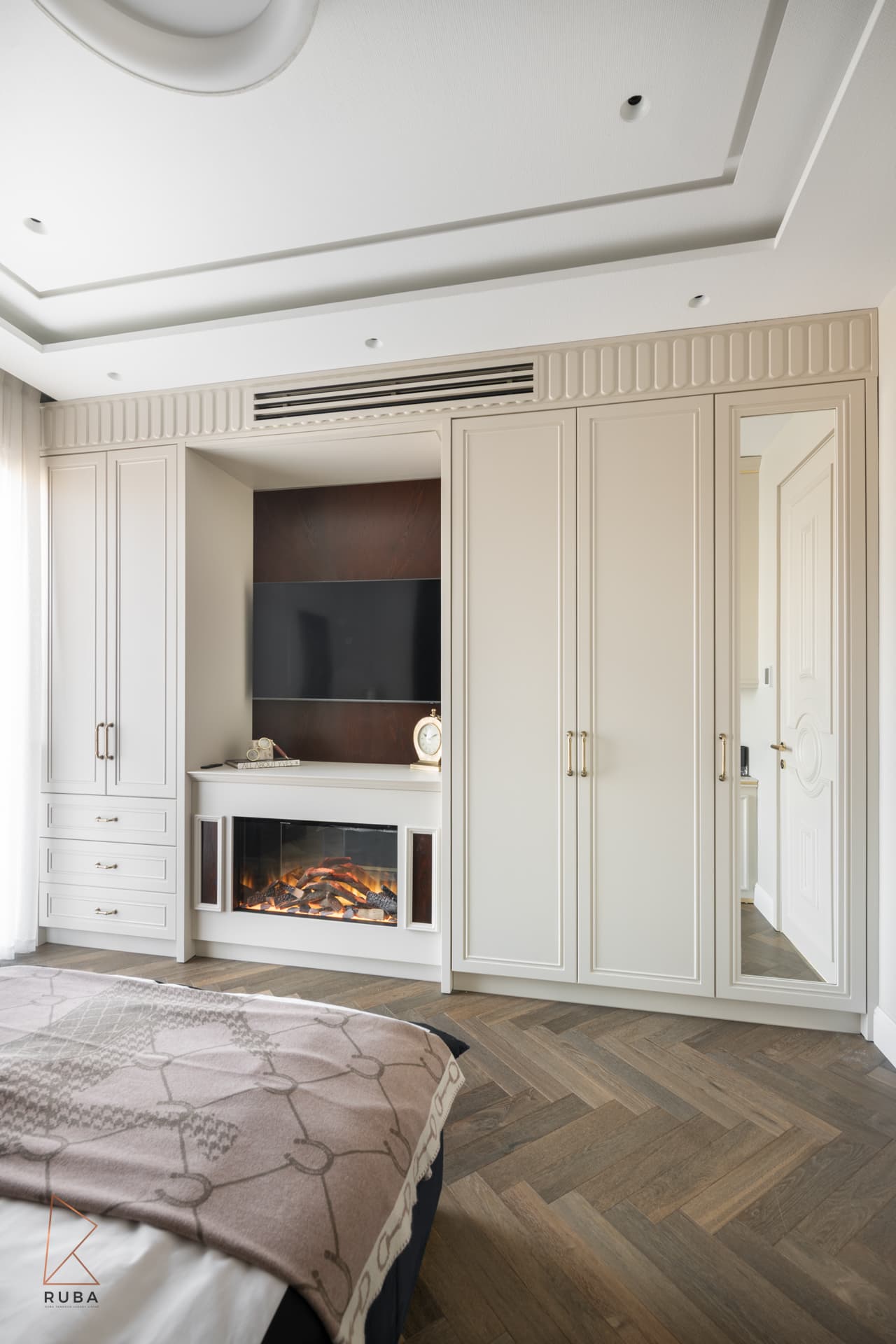 Kids bedroom wall of cream panelled wardrobes framing a media niche with a built-in fireplace in The Last Supper