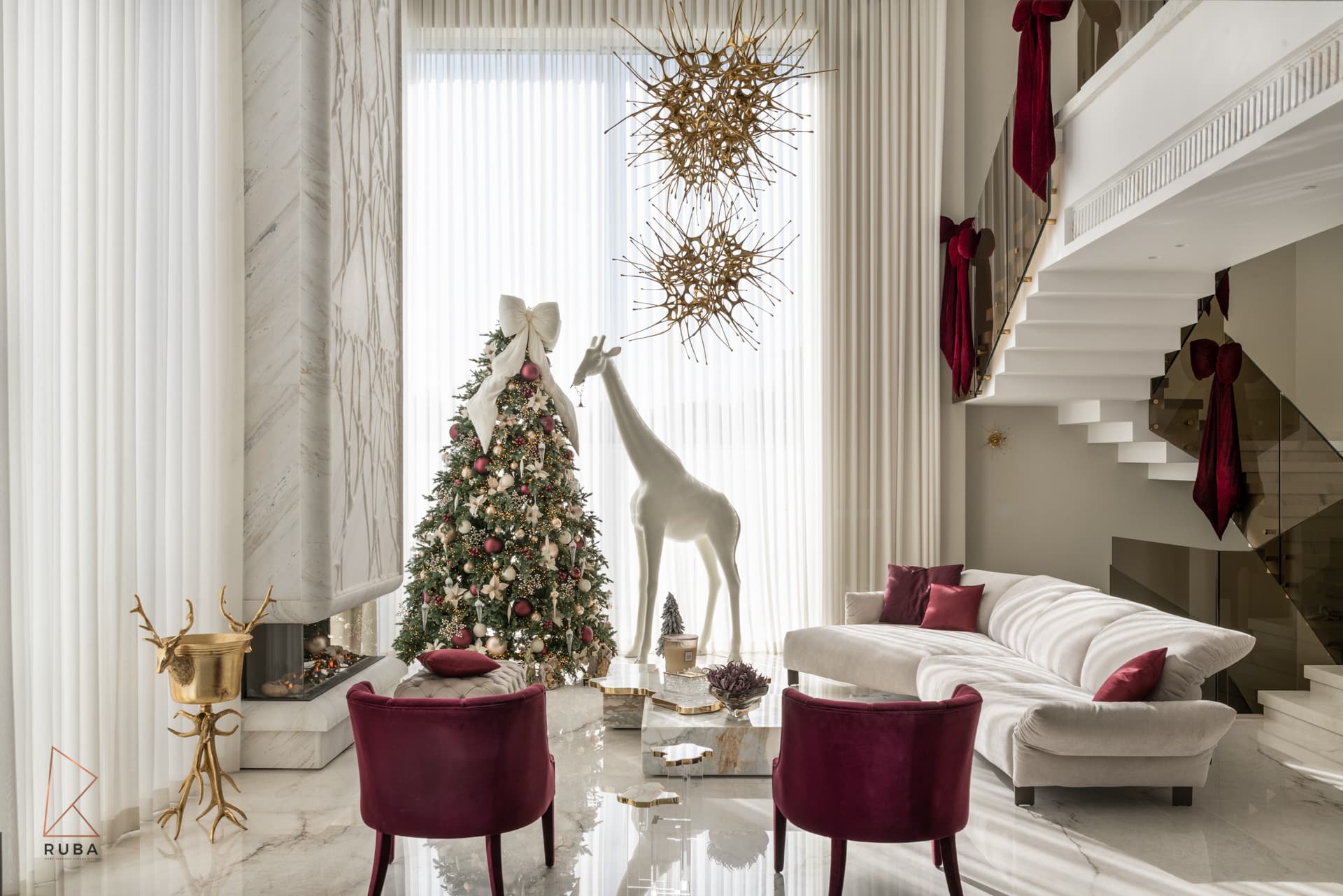 Double-height living room with a veined stone fireplace column, gold starburst chandeliers and burgundy velvet armchairs in The Last Supper