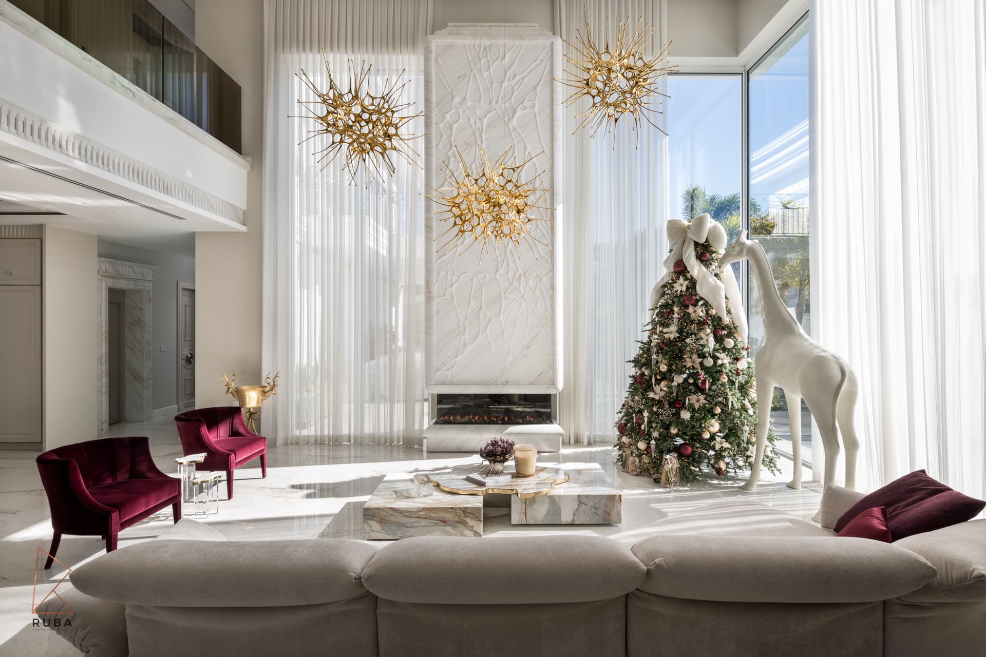 Living room seen from behind the sofa toward a carved stone fireplace wall and gallery balcony in The Last Supper