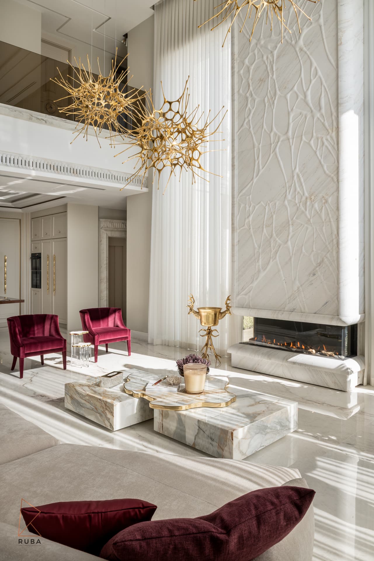 Living room looking toward a carved stone fireplace wall with veined stone coffee tables and burgundy cushions in The Last Supper