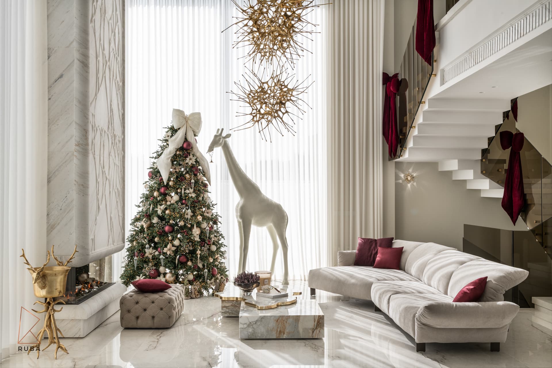 Living room with a floating white staircase, stone fireplace column, tufted ottoman and a cream sofa in The Last Supper