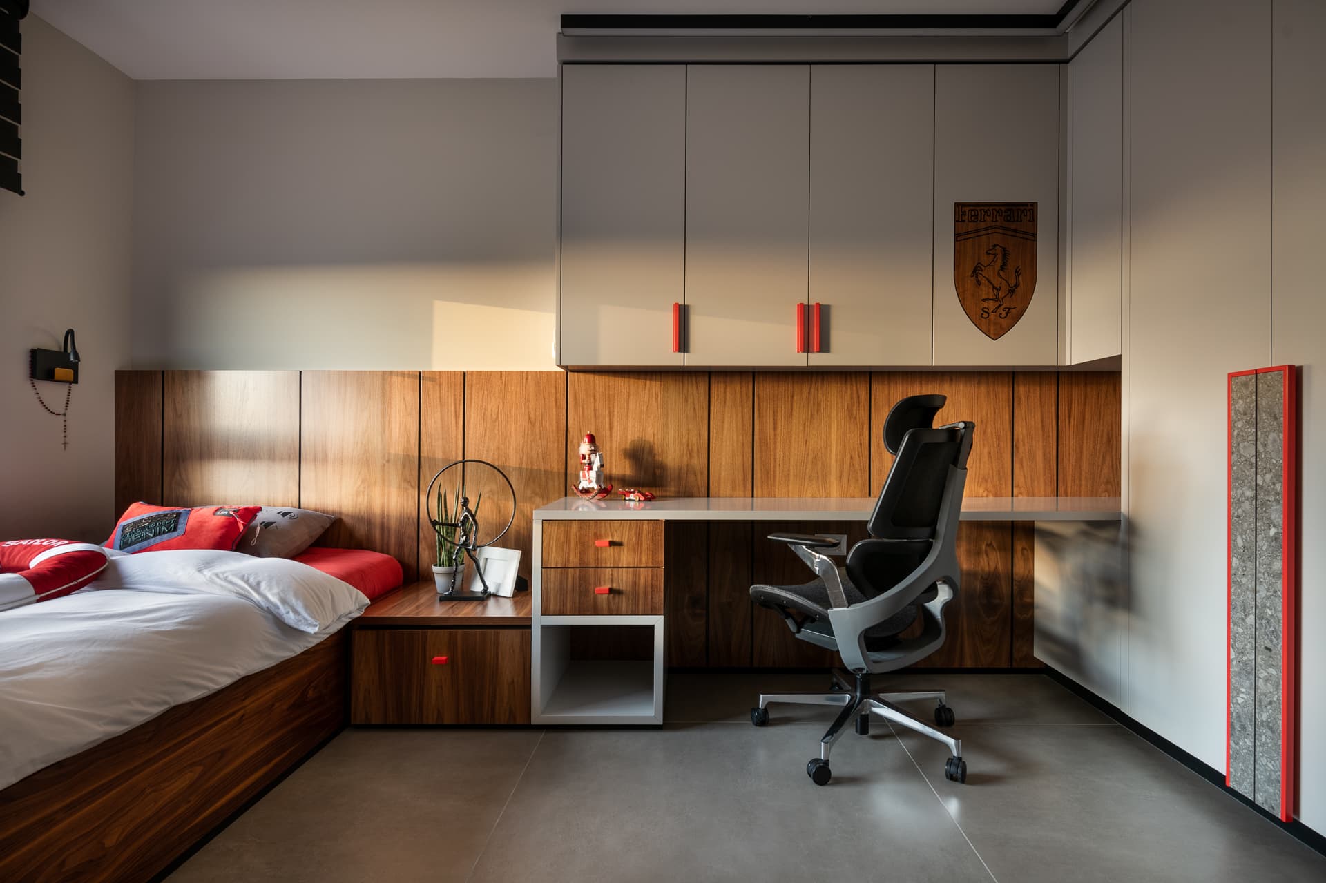Boys room with a walnut-panelled wall, built-in bed, floating white desk and red accent handles in Timeless Union