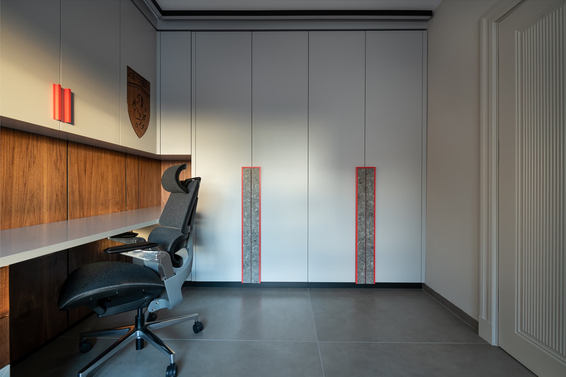 White full-height wardrobe with speckled stone pulls edged in red beside the walnut desk wall in the boys room of Timeless Union