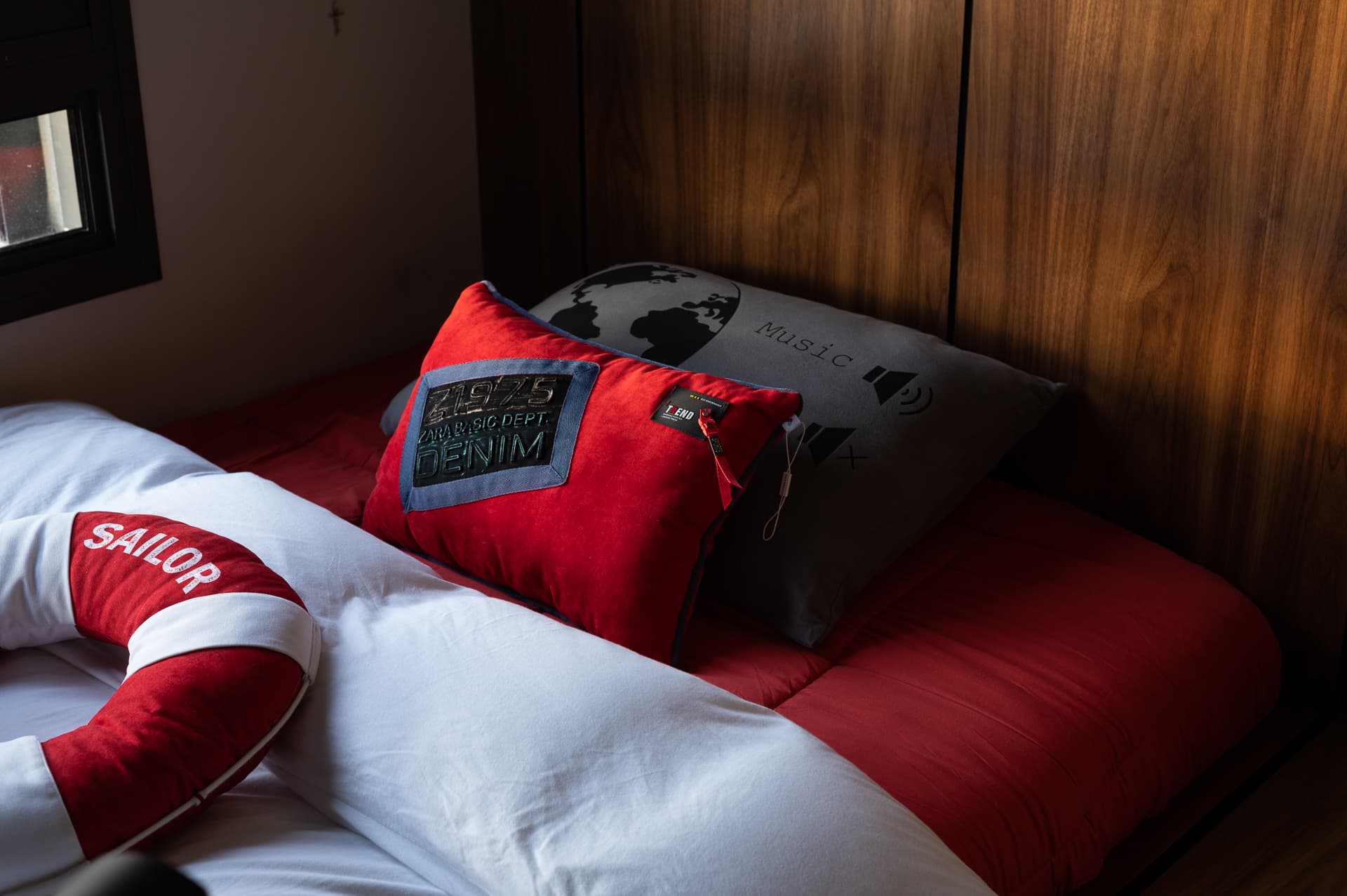 Red and white bedding with patterned cushions against warm walnut panelling in the boys room of Timeless Union