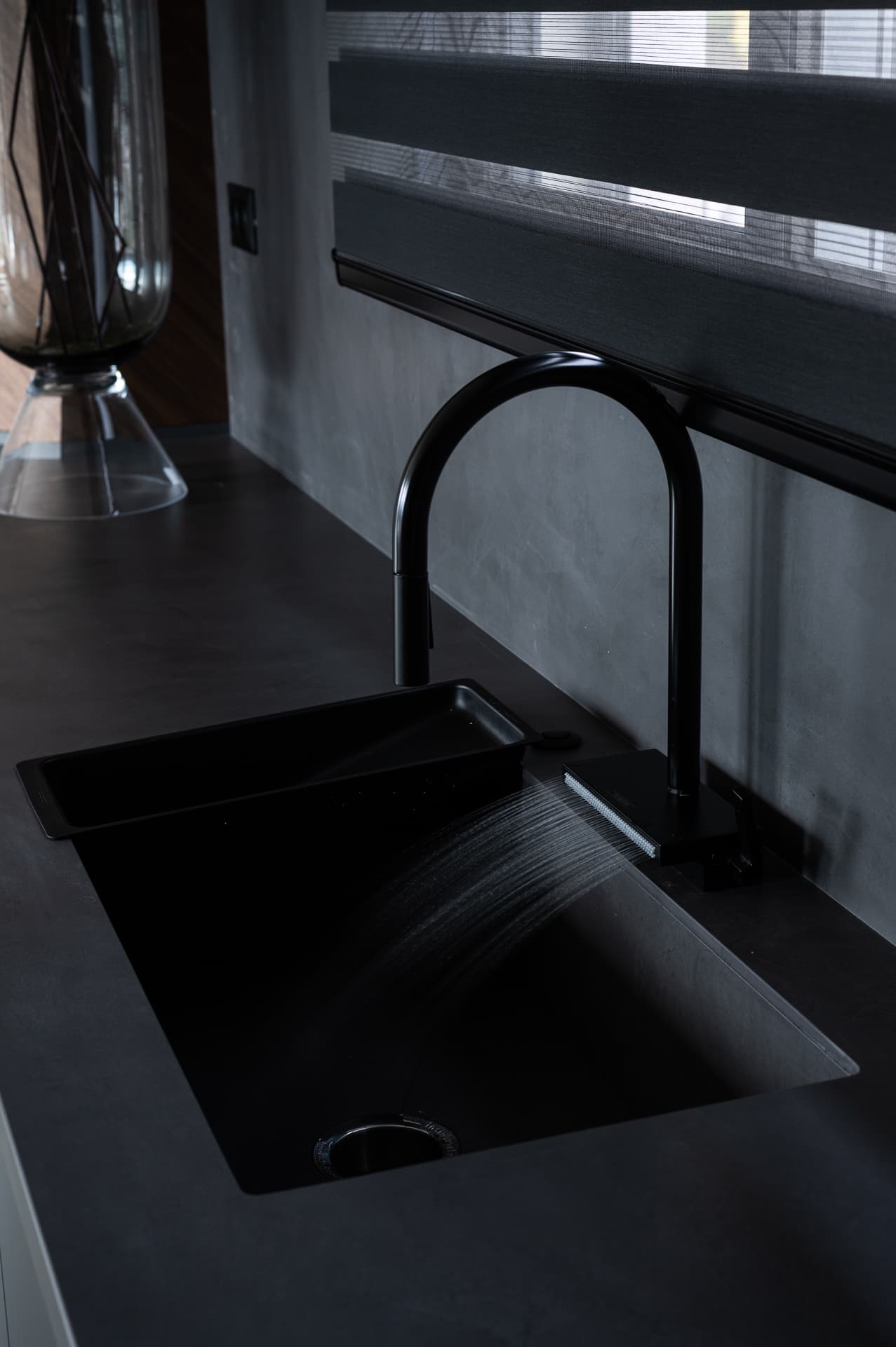 Matte black pull-down faucet spraying into a black undermount sink on a dark counter in Timeless Union
