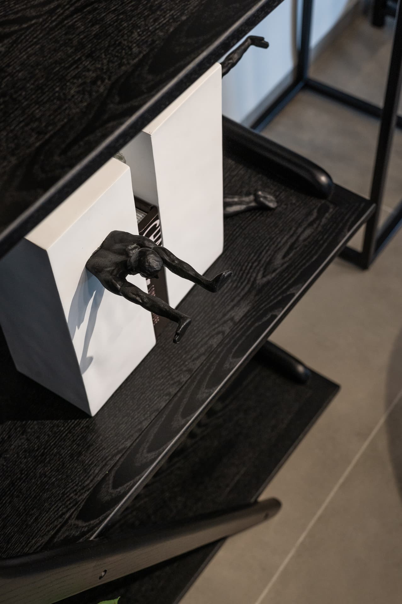 Climbing figure sculpture gripping white bookends on black wood-grain shelves in Timeless Union