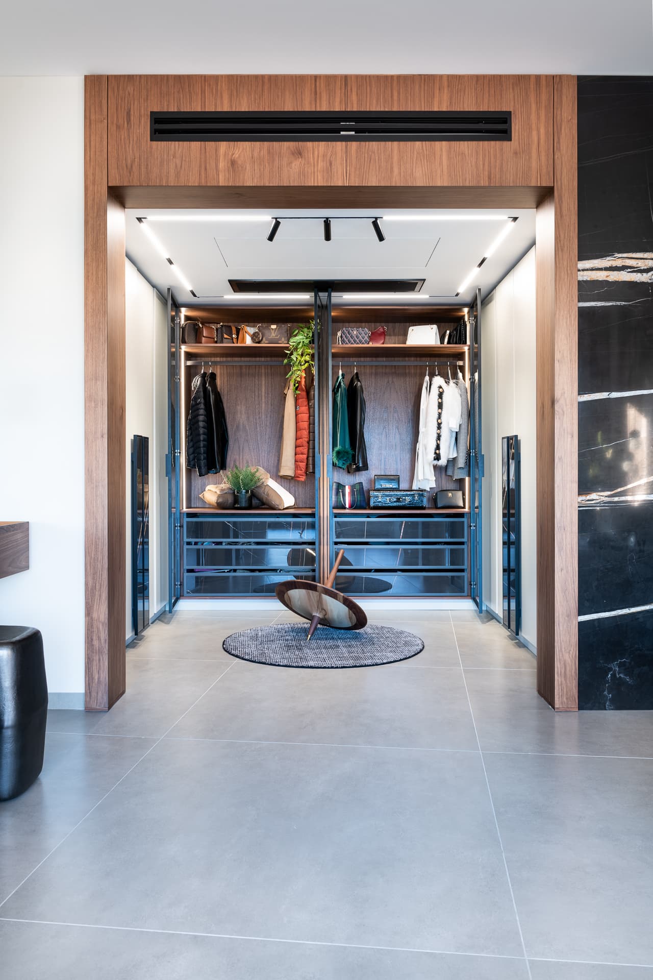 Walnut portal framing an open walk-in dressing room with lit walnut shelving and glass-front drawers in Timeless Union