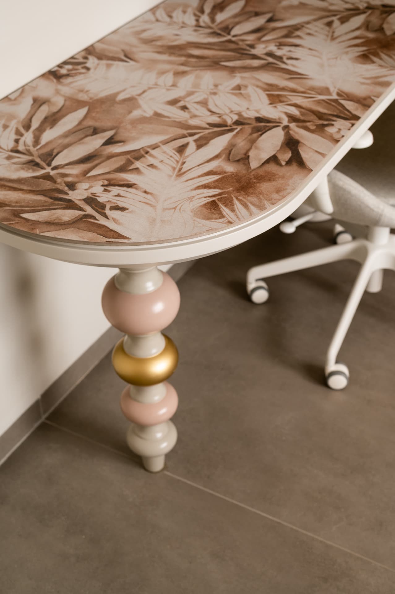 Botanical-print desktop resting on a turned leg with pink and gold beads in the girls room of Timeless Union