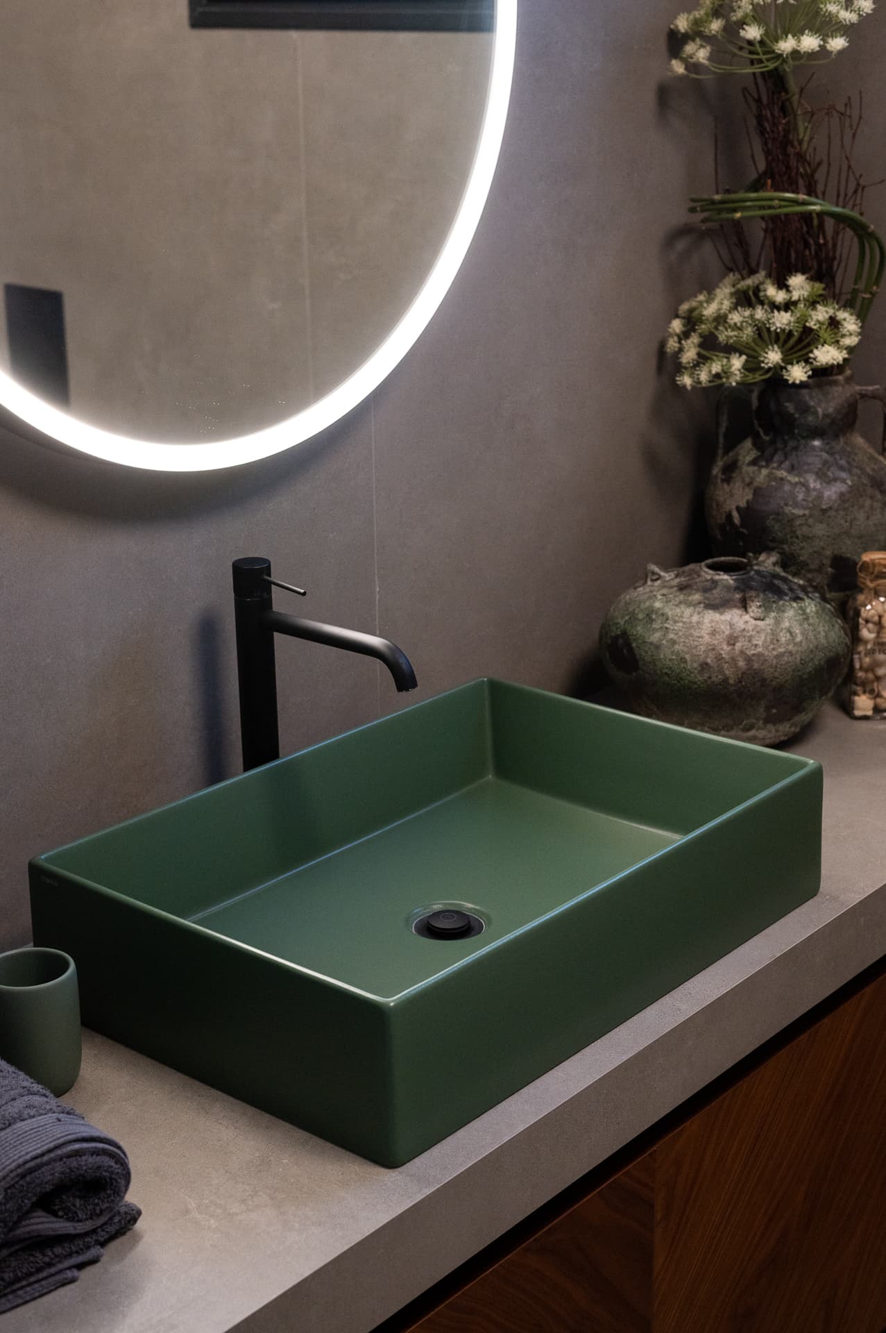Forest green rectangular basin with a black tall mixer under a backlit round mirror in the guest bathroom of Timeless Union