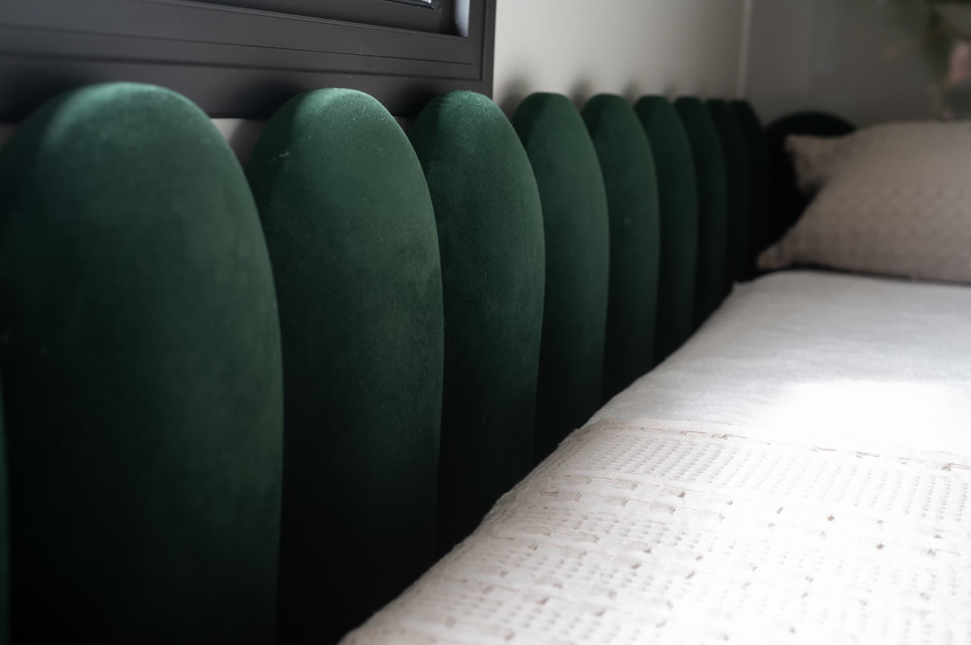Row of arched green velvet headboard panels running along a daybed with a textured cream throw in the guest bedroom of Timeless Union