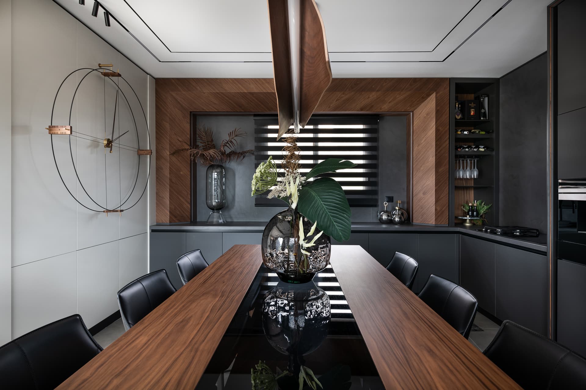 Split walnut table with a glass centre and a sculptural wire wall clock in the kitchen dining area of Timeless Union