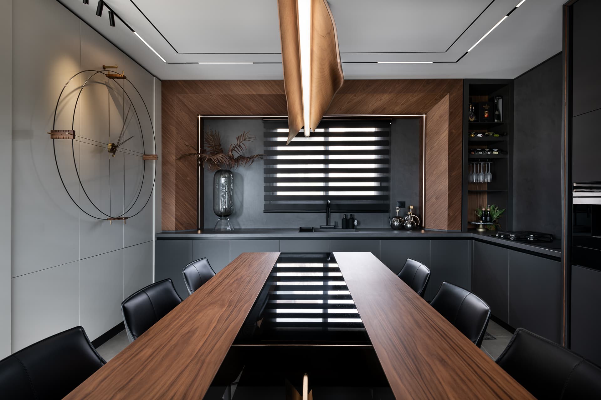 Symmetrical view of the walnut dining table, black leather chairs and walnut-framed window niche in the kitchen of Timeless Union